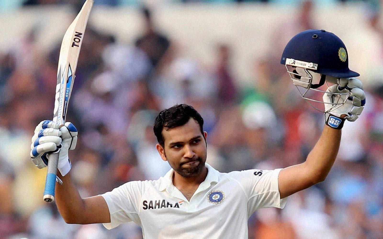 Rohit Sharma 桌布 壁紙 — 身穿白色球衣的板球運動員在歡呼的人群前高舉球棒和頭盔，擺出勝利姿勢。