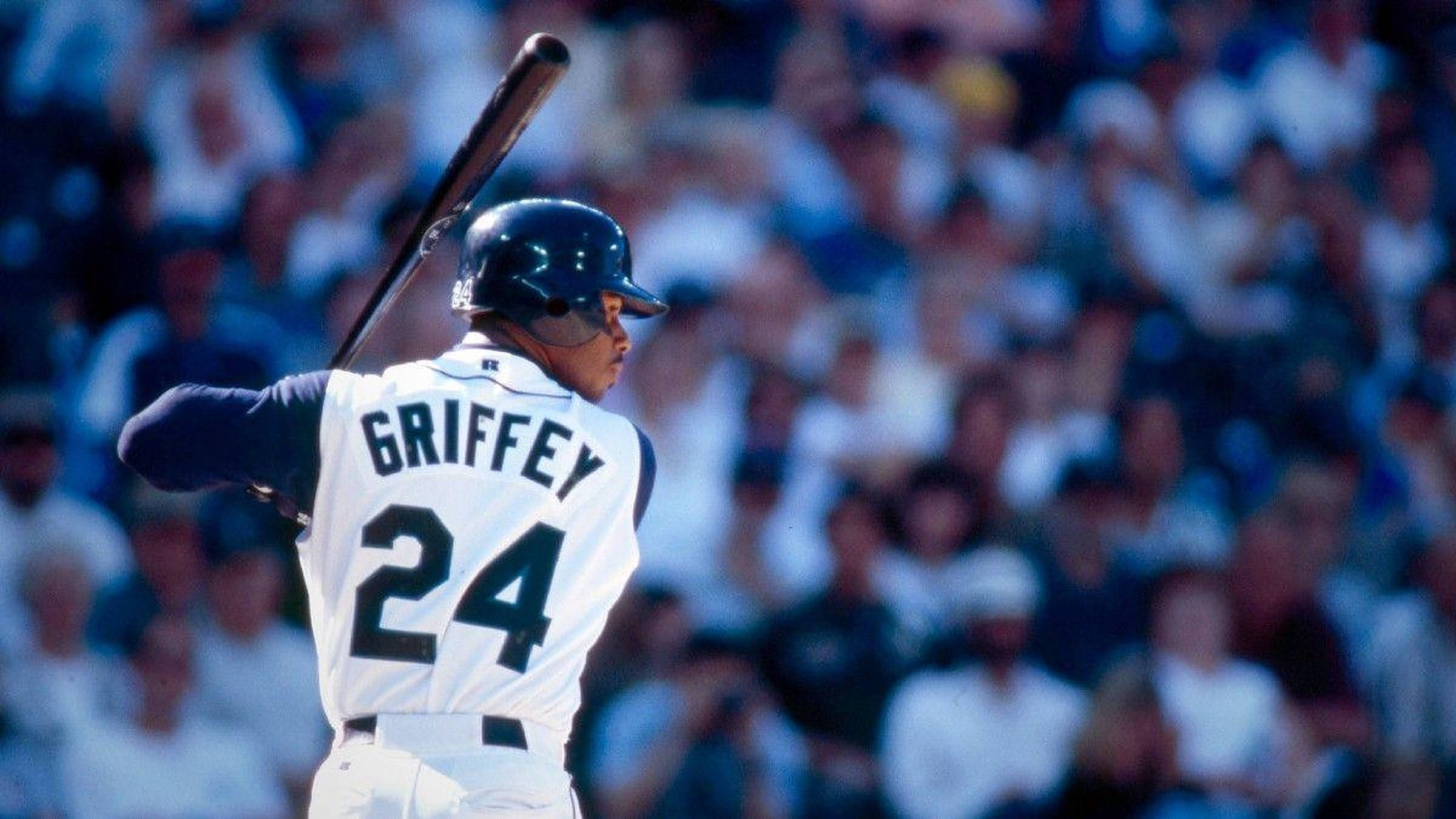 ken 桌布 壁紙 — 身穿白色球衣的棒球選手Griffey 24號在球場準備揮棒，背景是模糊的人群。