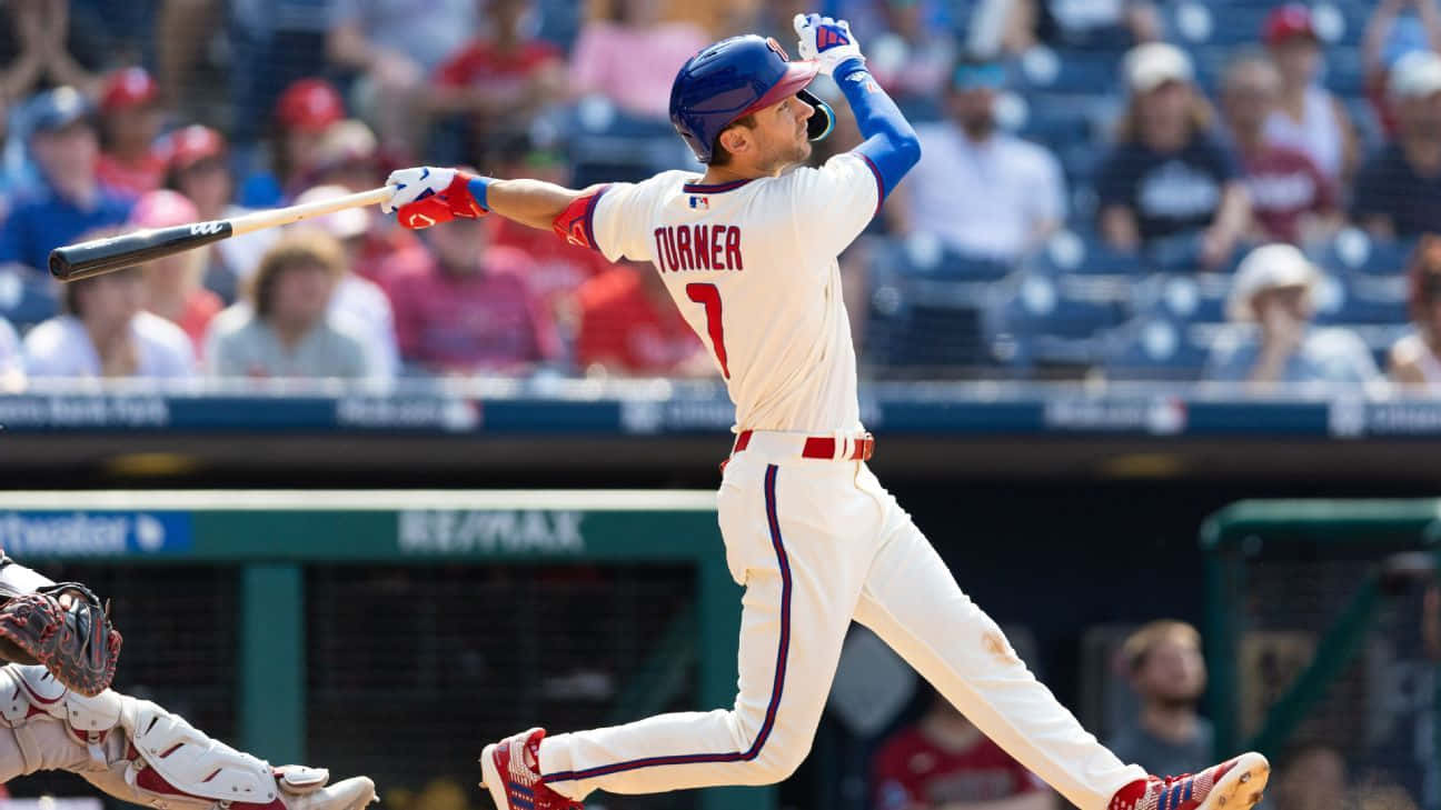Trea Turner Phillies 桌布 壁紙 — 身穿白色球衣的棒球選手Turner在揮棒中途，背景有觀眾。