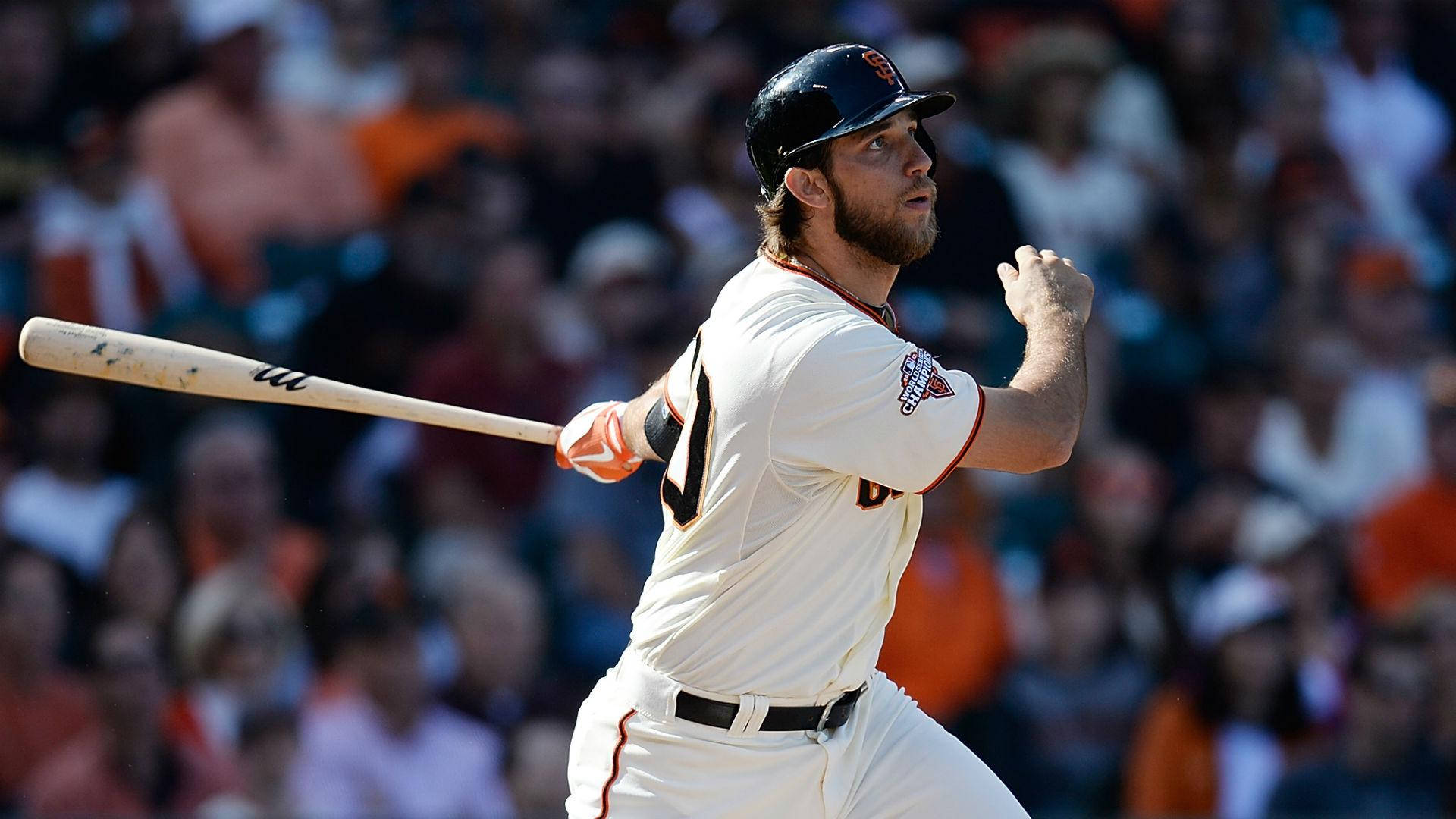 madison bumgarner 桌布 壁紙 — 身穿白色球衣的棒球選手在揮棒中途，專注地對抗模糊的球場觀眾。