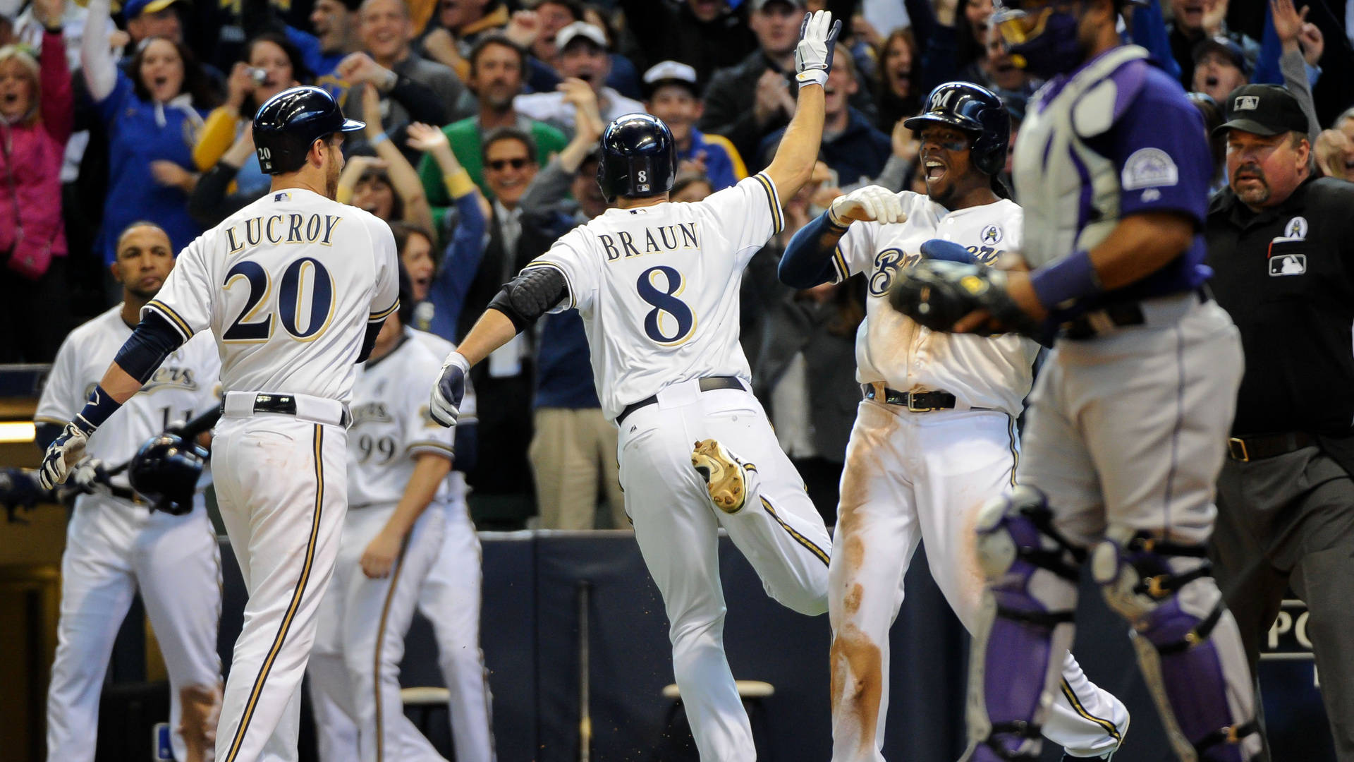 Brewers 桌布 壁紙 — 身穿白色球衣的棒球選手在球場燈光下以擊掌和歡樂表情慶祝全壘打。