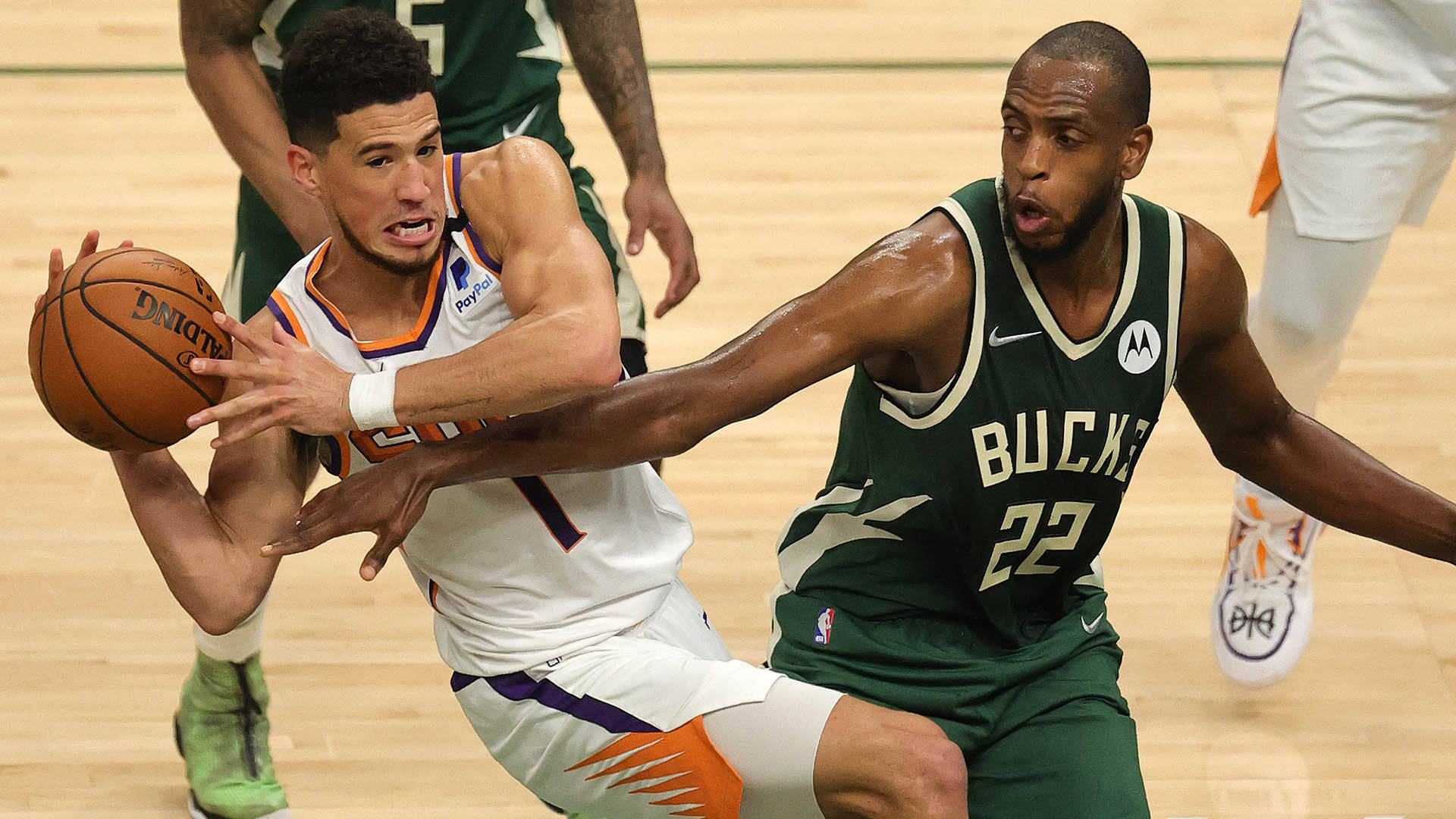 Khris Middleton 桌布 壁紙 — 身穿白色球衣的激烈籃球運動員在拋光硬木球場上的一場緊湊比賽中突破身穿綠色球衣的防守球員。