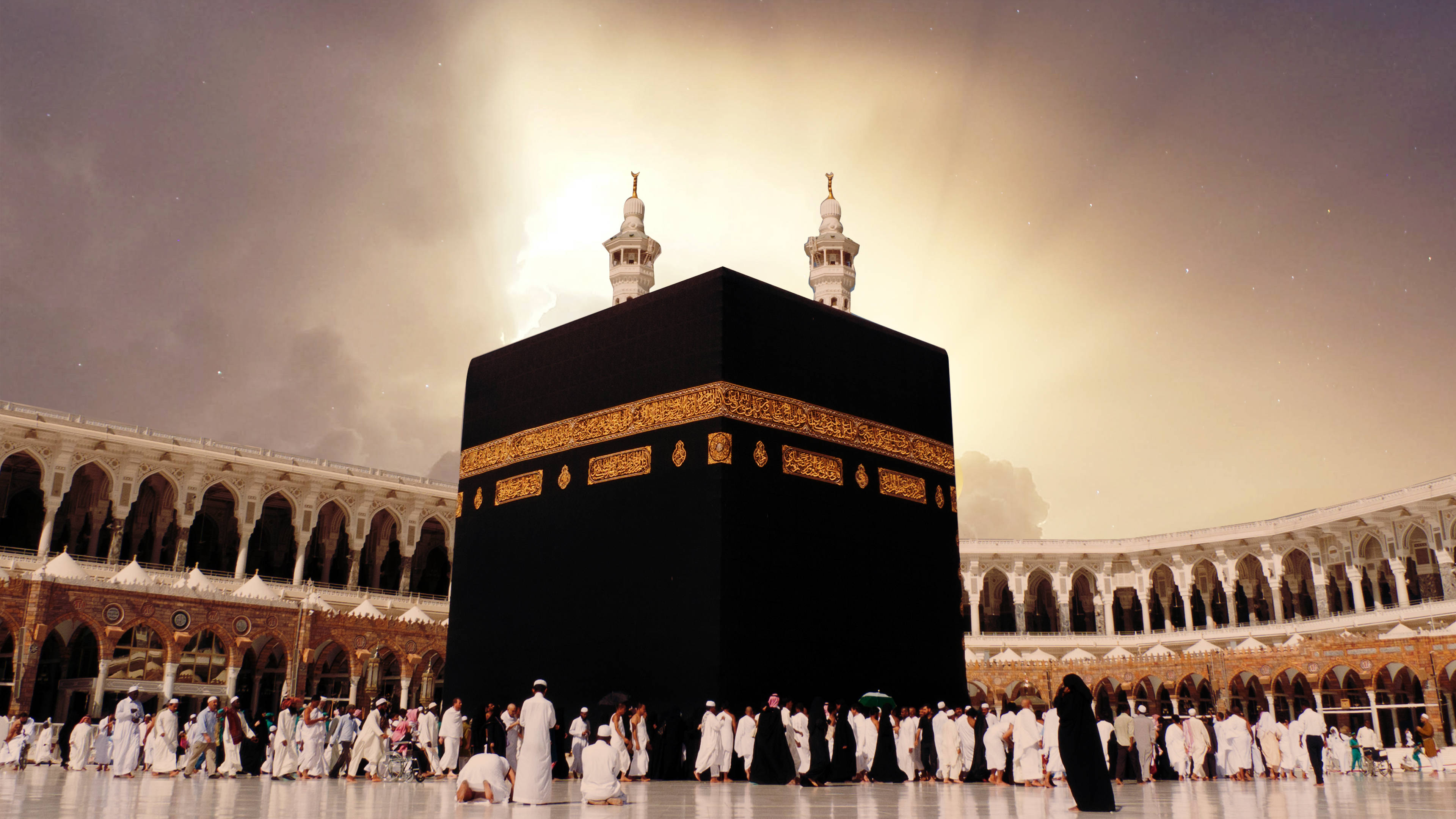 muslim 桌布 壁紙 — 身穿白衣的朝聖者在麥加戲劇性的金色天空下繞行黑色天房。