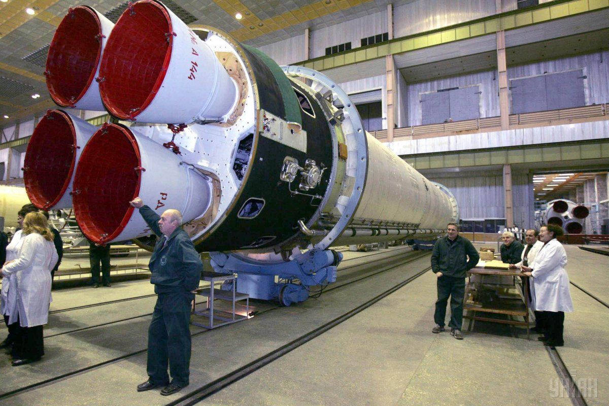 Aerospace 桌布 壁紙 — 身穿白袍的工程師在廣闊的工業機庫內檢查一枚帶有紅色噴嘴的巨大火箭。