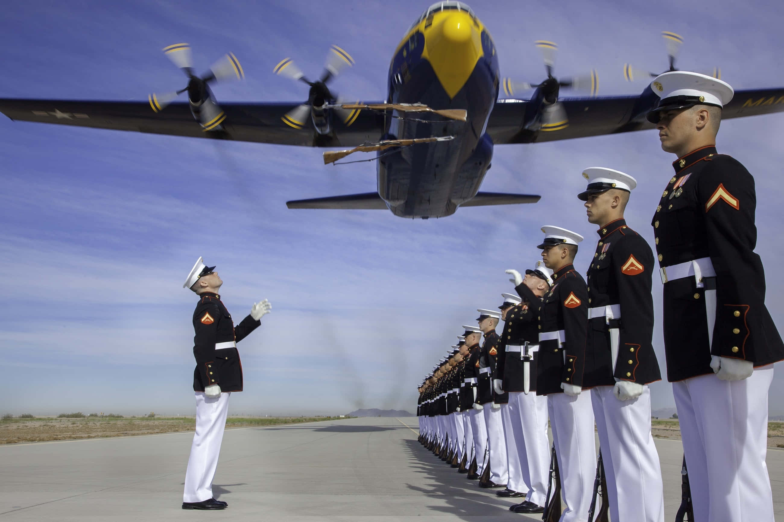 Marines 桌布 壁紙 — 身穿禮服的海軍陸戰隊員在機場立正，一架大型藍黃色螺旋槳飛機低空飛過他們頭頂。