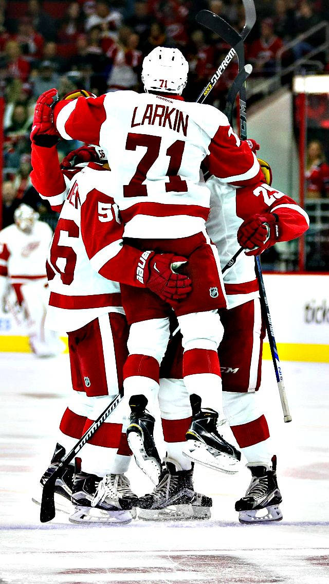 hockey 桌布 壁紙 — 身穿紅白球衣的冰上曲棍球運動員在冰上高舉手臂和球棍慶祝進球。