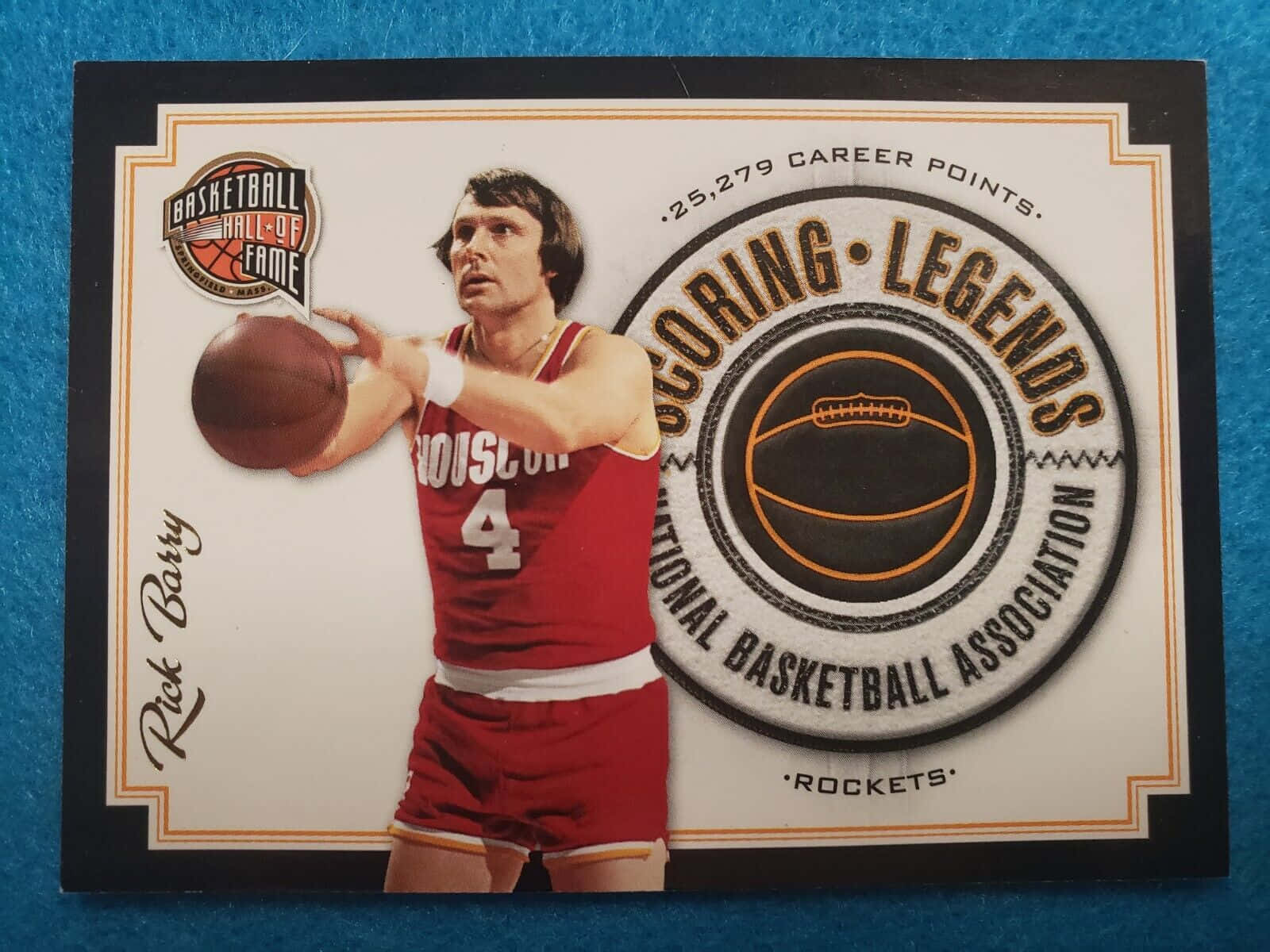 Houston Rockets 桌布 壁紙 — 身穿紅色休士頓火箭隊球衣的Rick Barry，在藍色紋理背景前，準備在一張復古名人堂交易卡上投籃。