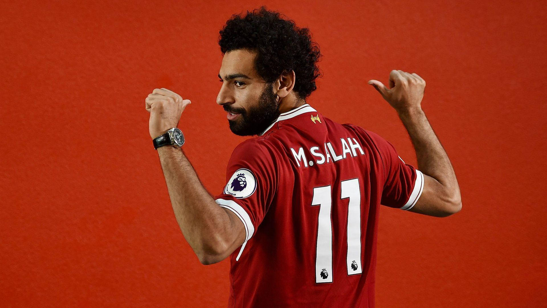 Salah 桌布 壁紙 — 身穿紅色利物浦球衣的足球員穆罕默德·薩拉赫在純紅色背景前舉起拳頭慶祝。