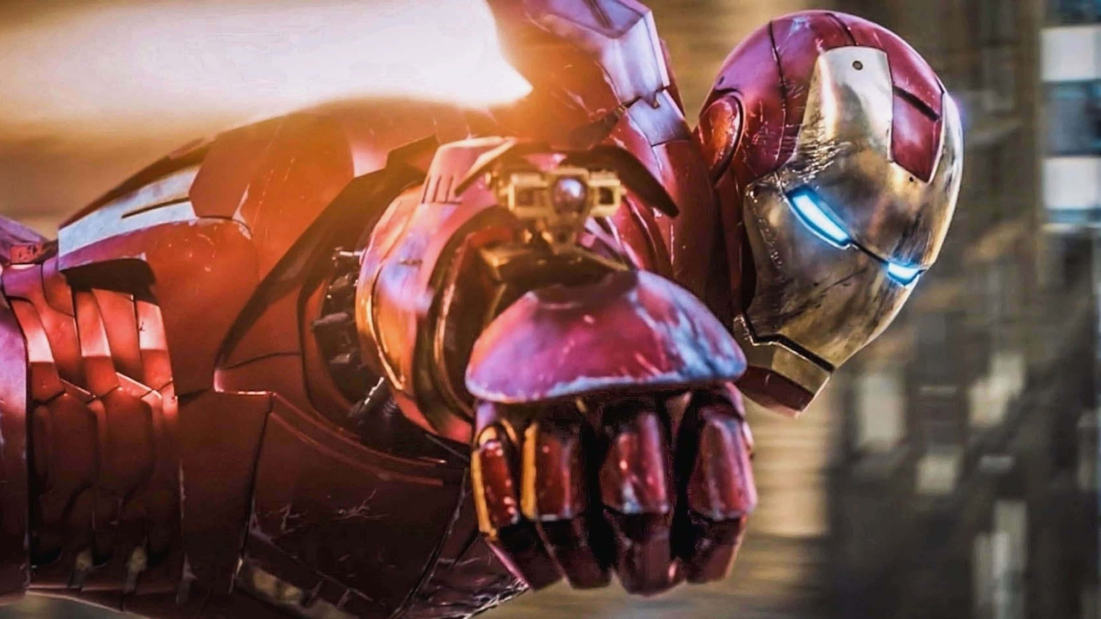 4K Marvel 壁紙 桌布 壁紙 — 身穿紅色和金色盔甲的鋼鐵人，在模糊的城市景觀背景下，伸出他的手，眼睛發出藍光。
