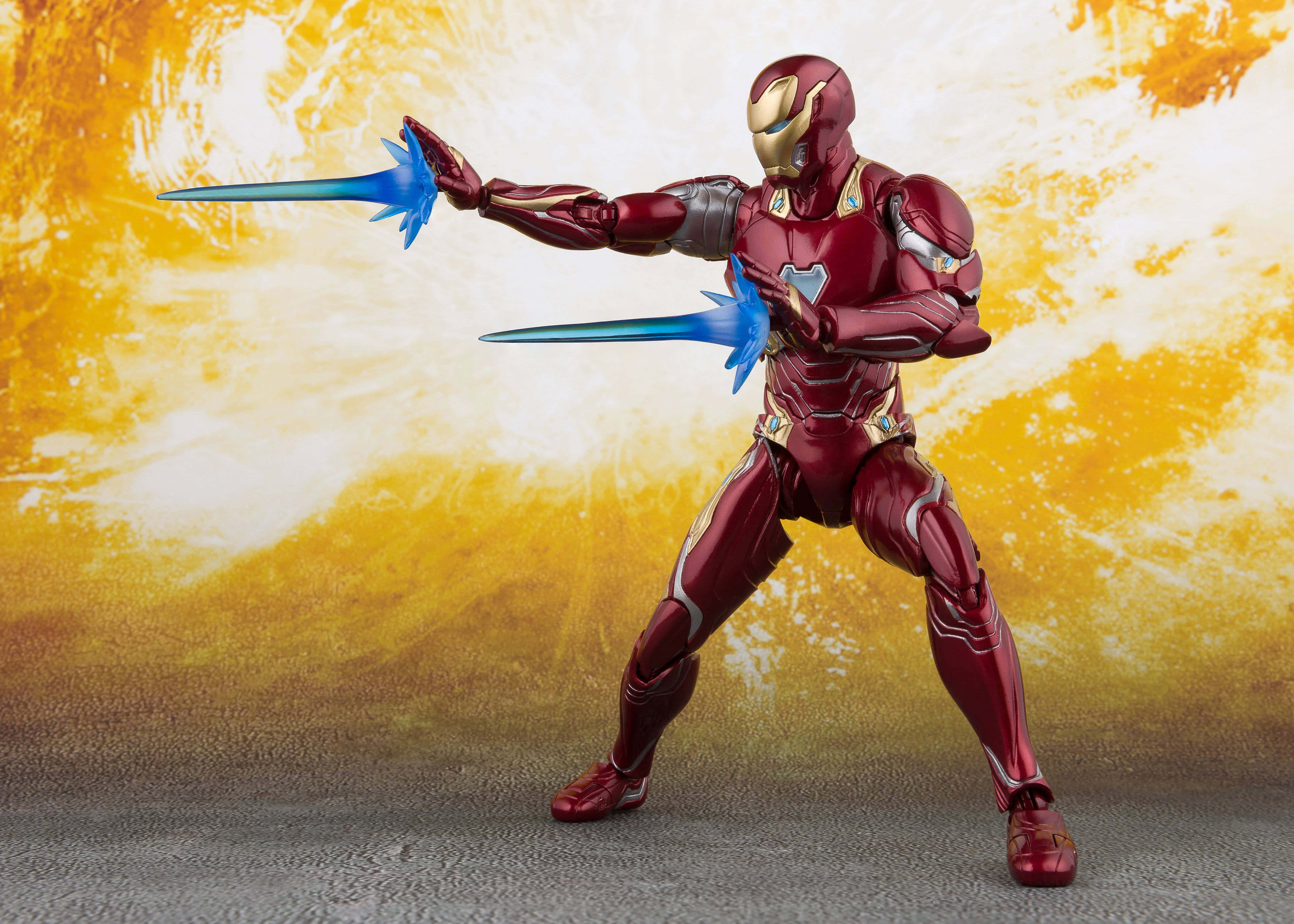 Iron Man Action Figures 桌布 壁紙 — 身穿紅色和金色盔甲的鋼鐵人動作人偶，在熾熱的黃色和白色背景下發射藍色斥力光束。