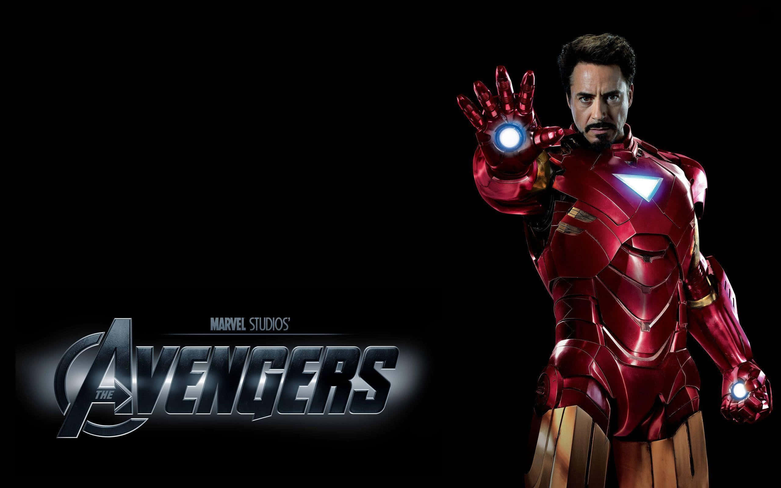Iron Man Movies 桌布 壁紙 — 身穿紅色和金色裝甲的鋼鐵人在帶有復仇者聯盟標誌的黑色背景前伸出發光的斥力炮手。