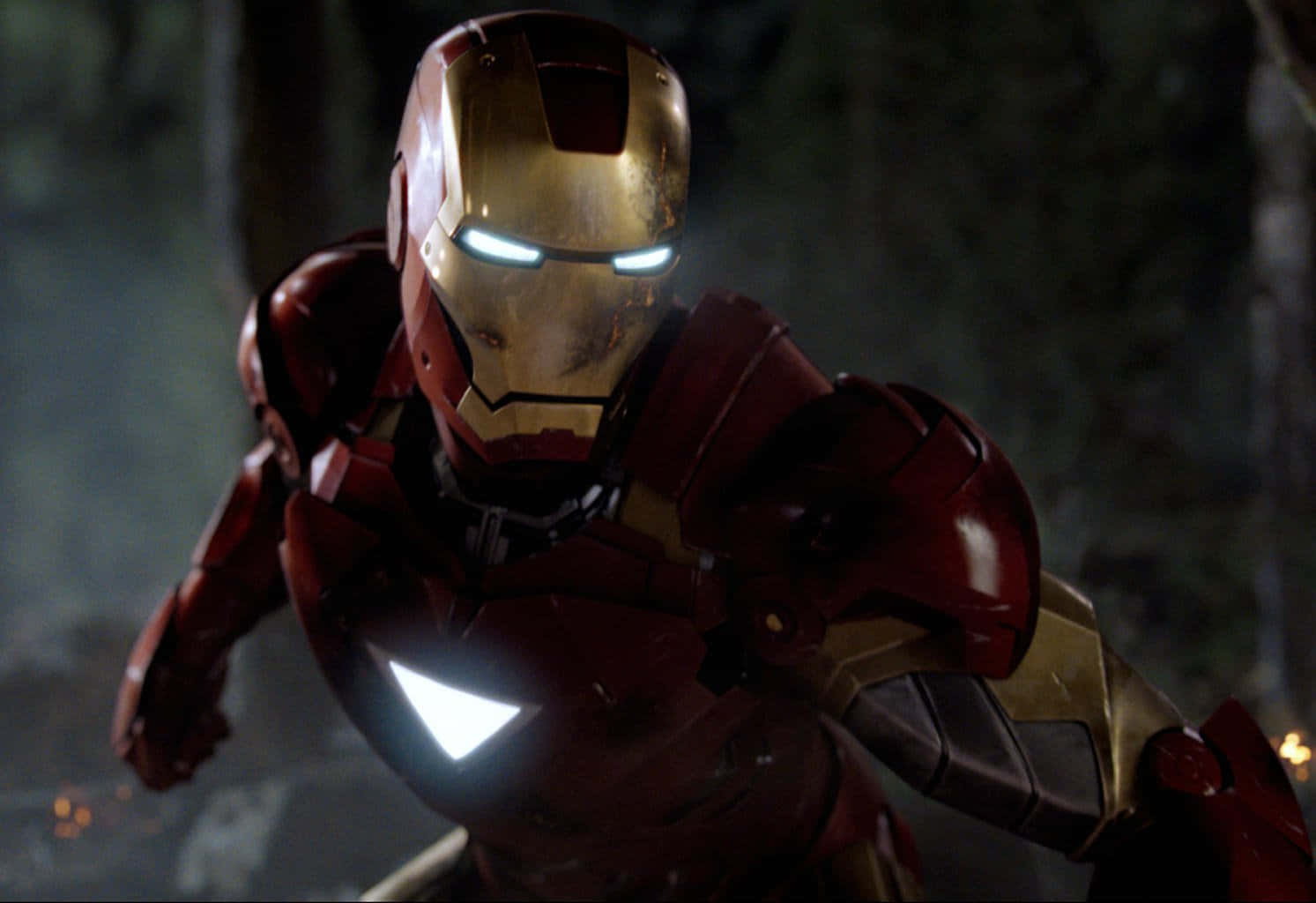 Marvel Movie 桌布 壁紙 — 身穿紅色和金色裝甲的鋼鐵人在黑暗的森林中蹲下，眼睛和胸部弧形反應堆發光。