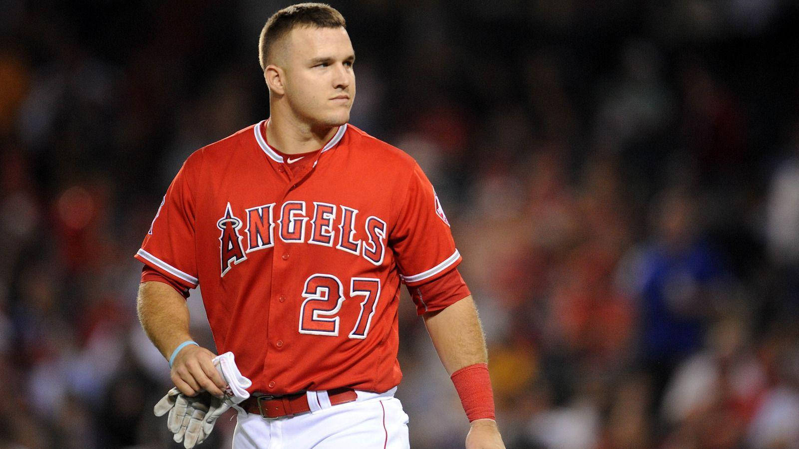 Mike Trout 桌布 壁紙 — 身穿紅色天使隊27號球衣的棒球運動員在球場燈光下莊嚴地走在場地上。