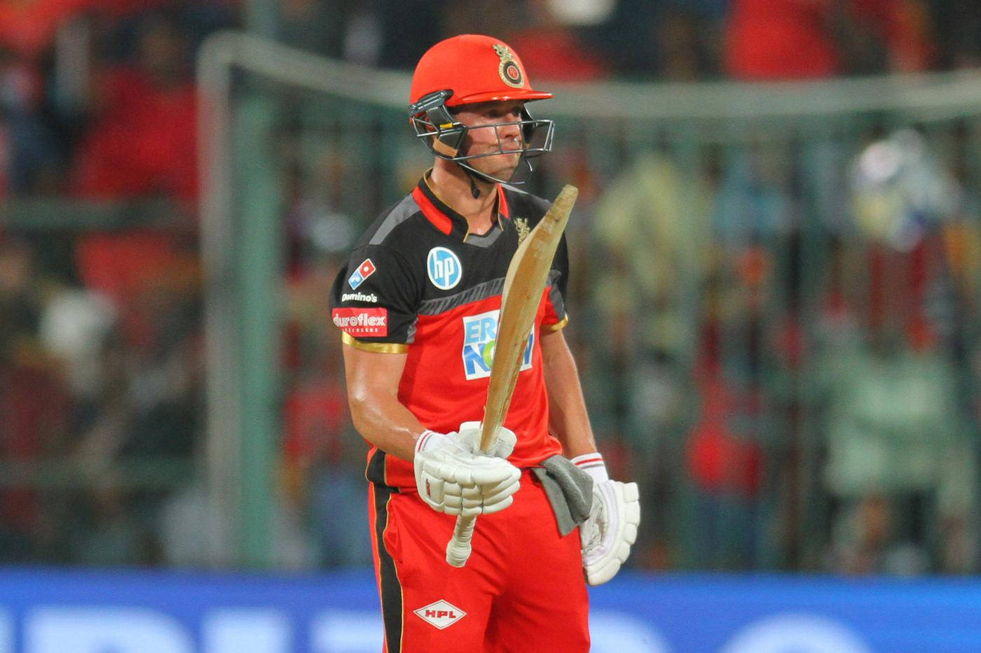 royal challengers bangalore 桌布 壁紙 — 身穿紅色球衣的板球選手手持球棒，專注地站在球場上，球場燈光照射下。