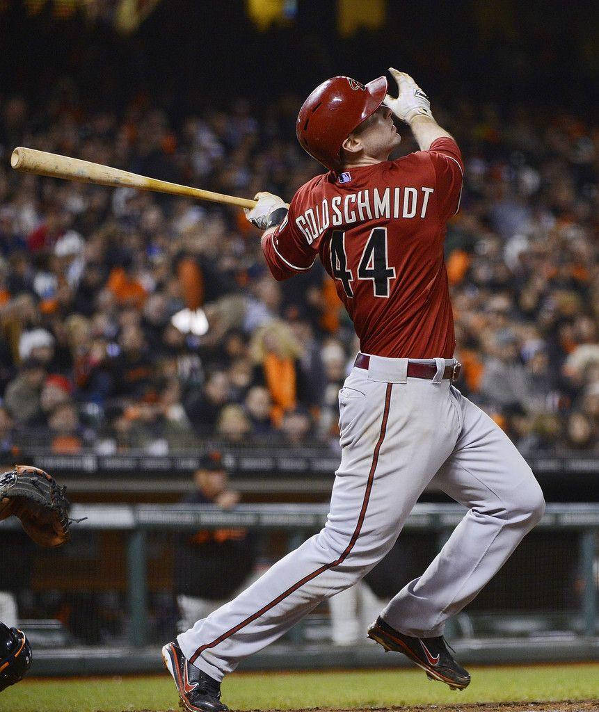 Paul Goldschmidt 桌布 壁紙 — 身穿紅色球衣的棒球選手 Bryce Harper 在球場燈光下，背景有觀眾，揮棒中段揮動球棒。