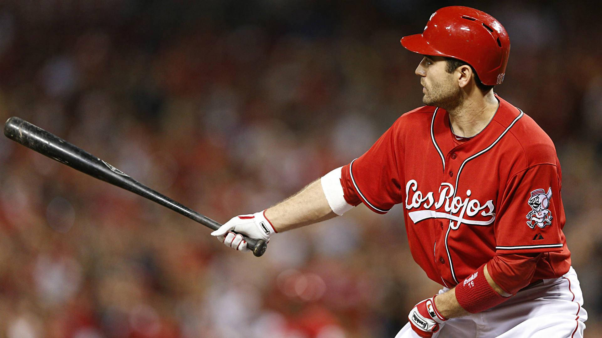 Joey Votto 桌布 壁紙 — 身穿紅色球衣的棒球選手在揮棒中途，專注地對著模糊的球場觀眾揮棒。