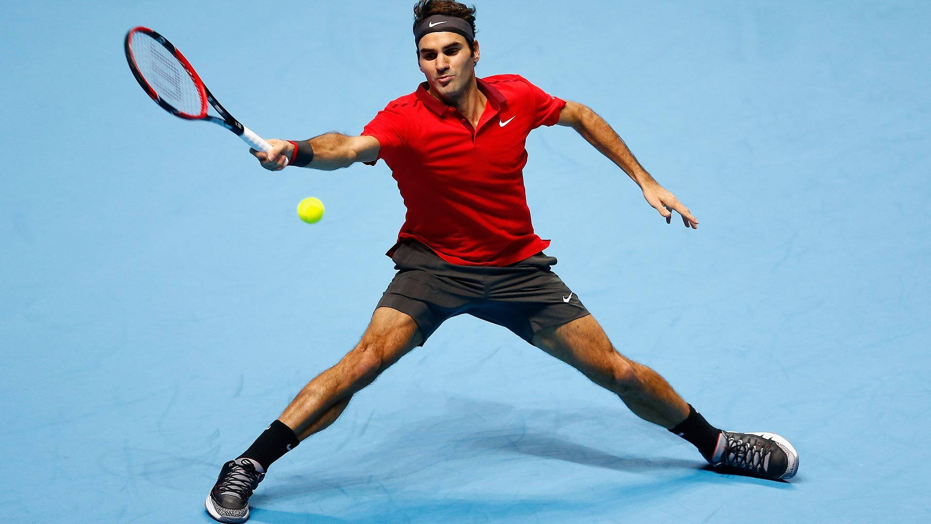 roger 桌布 壁紙 — 身穿紅色球衣的網球選手向前猛衝，在藍色球場上以高度專注擊打黃色球。