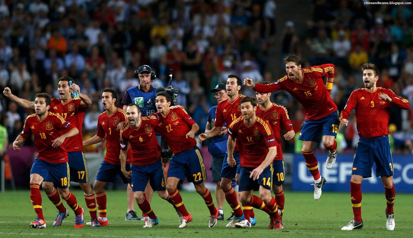 Spain 桌布 壁紙 — 身穿紅色球衣的西班牙足球員在球場燈光下的綠色草地上瘋狂慶祝，背景是歡呼的球迷。