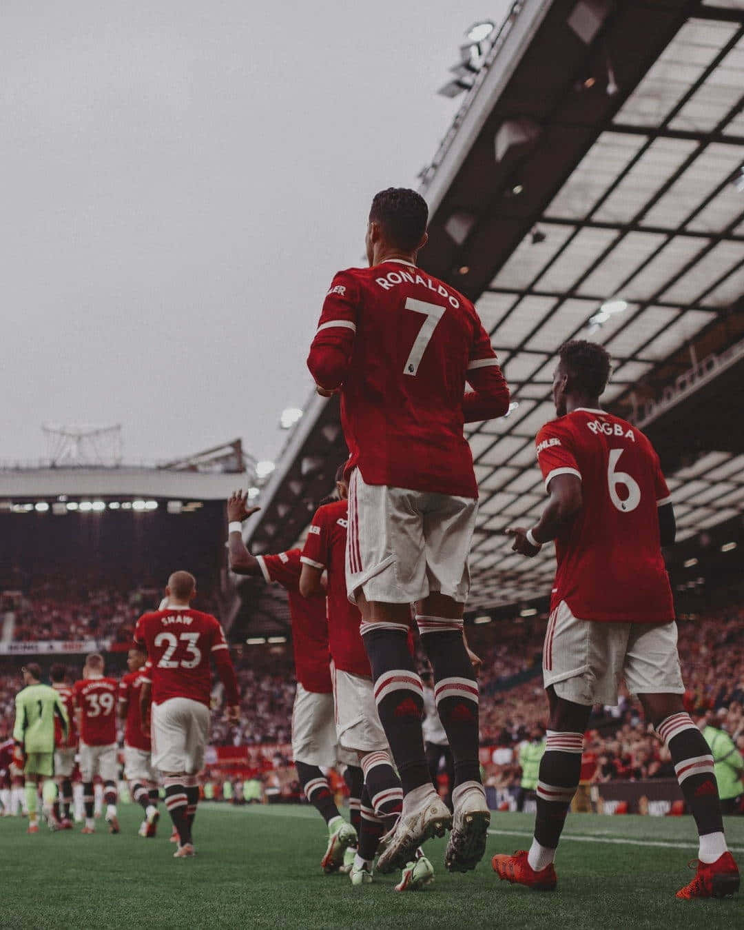 Manchester United Team 桌布 壁紙 — 身穿紅色球衣的足球運動員在綠色球場上慶祝，球場燈光下，看台上有球迷。