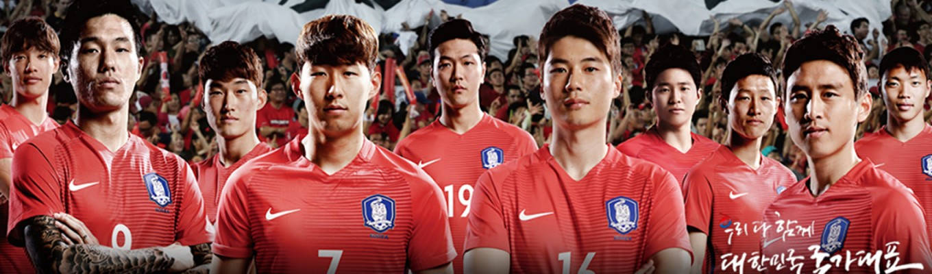Football Players 桌布 壁紙 — 身穿紅色球衣的韓國足球隊球員自信地擺姿勢，身後有揮舞旗幟的球迷。