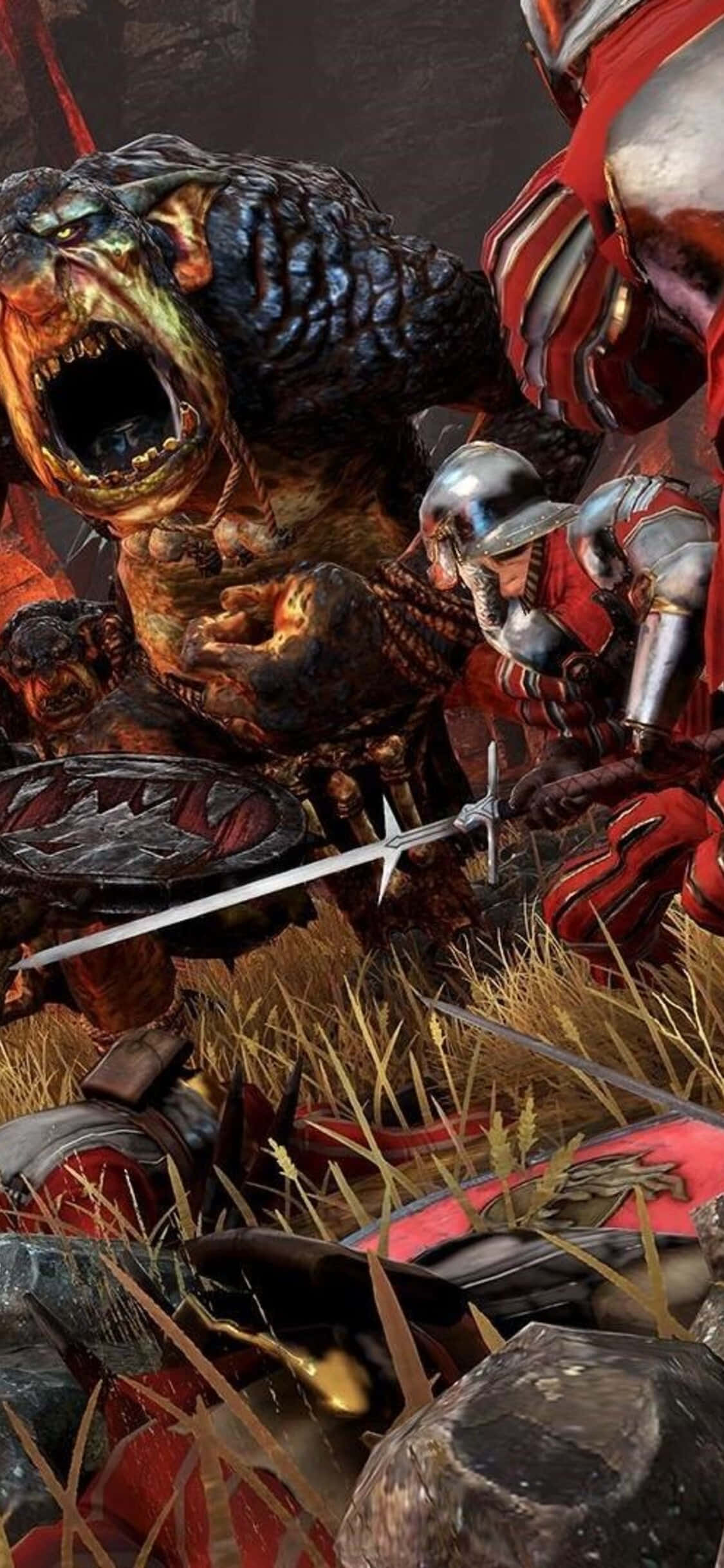 iPhone X Total War Warhammer 桌布 壁紙 — 身穿紅色盔甲的騎士在草地上與一隻擁有發光眼睛和鋒利牙齒的怪獸戰鬥。