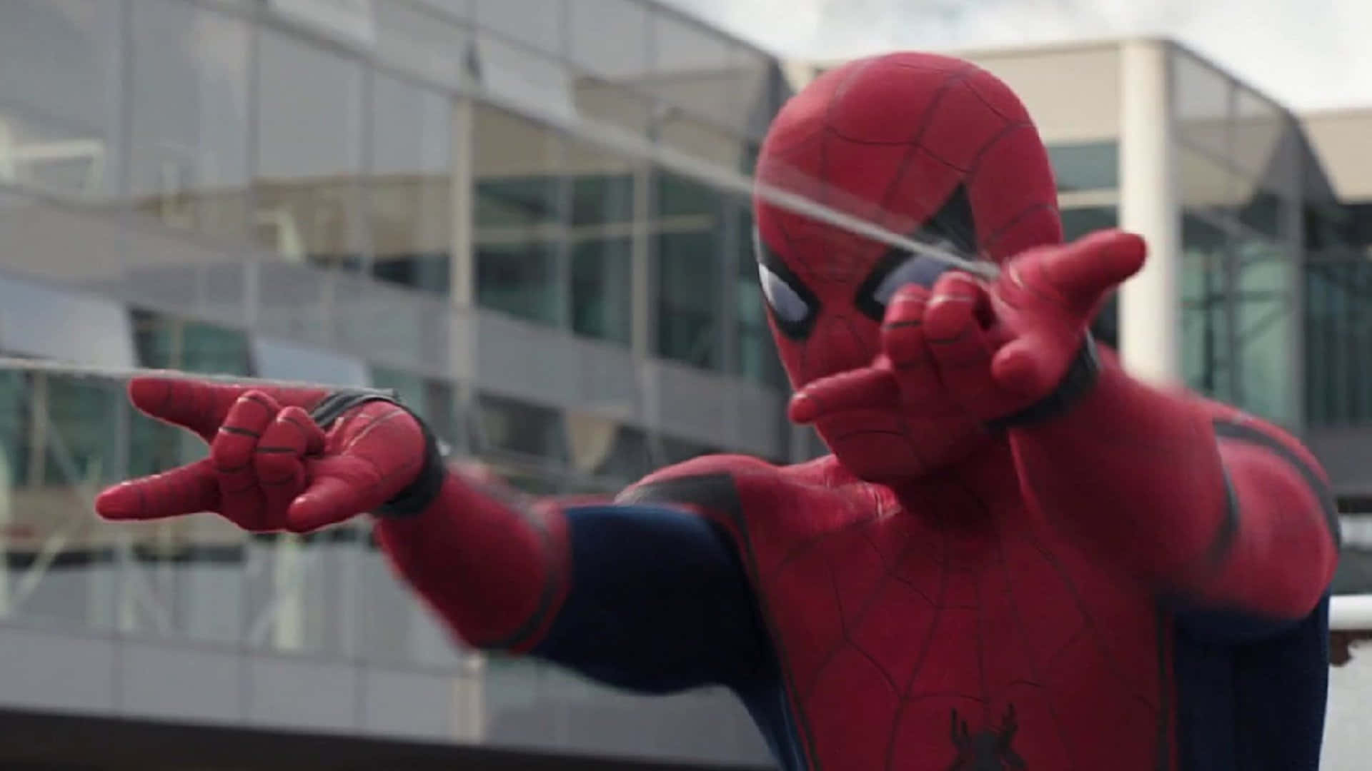 Spider-man Web Shooter 桌布 壁紙 — 身穿紅藍戰衣的蜘蛛人，在玻璃大廈背景下從手中射出蜘蛛絲。