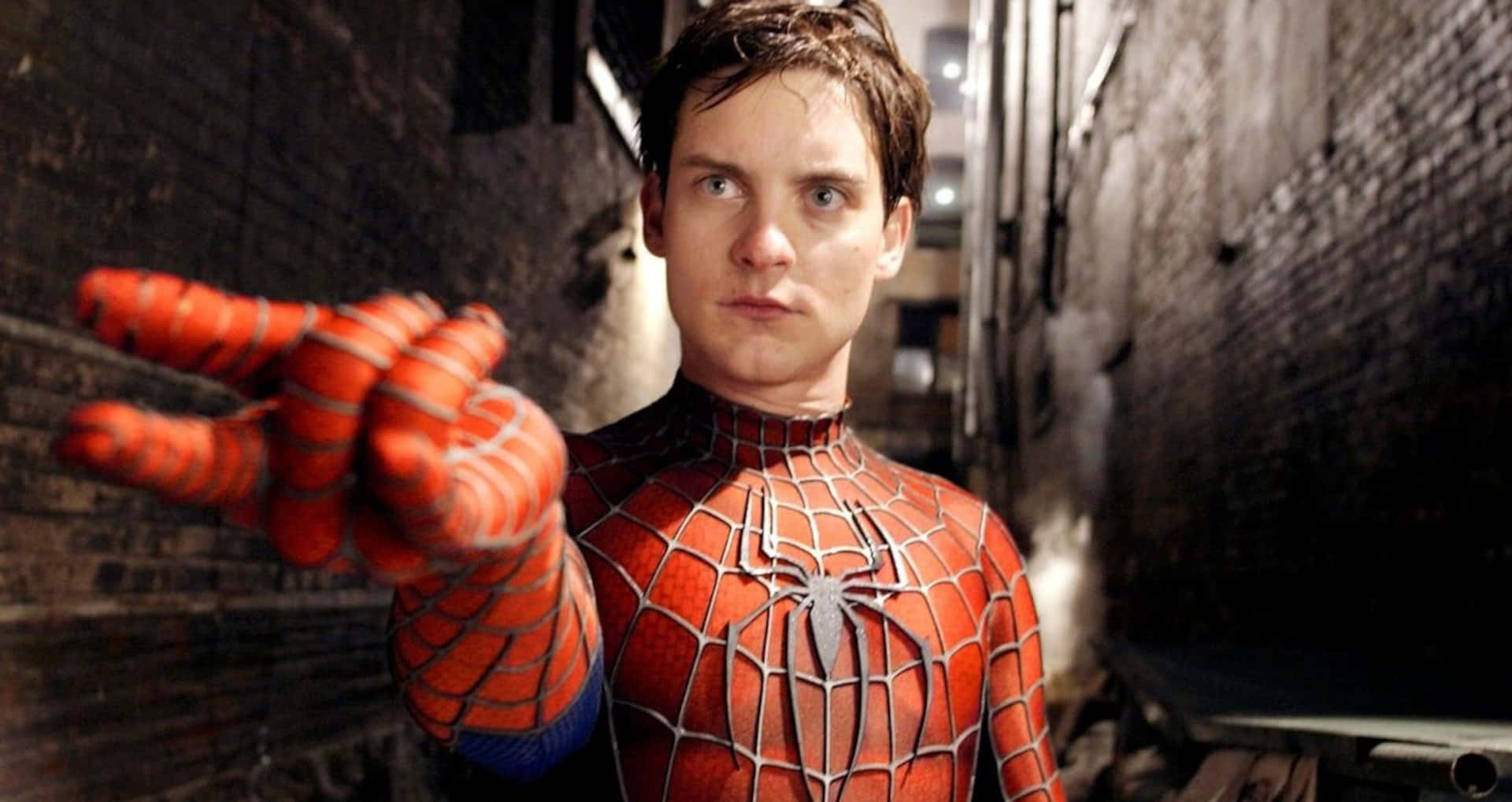 Spider-man Web Shooter 桌布 壁紙 — 身穿紅藍戰衣的蜘蛛人站在骯髒的小巷中，專注地向前伸出手。