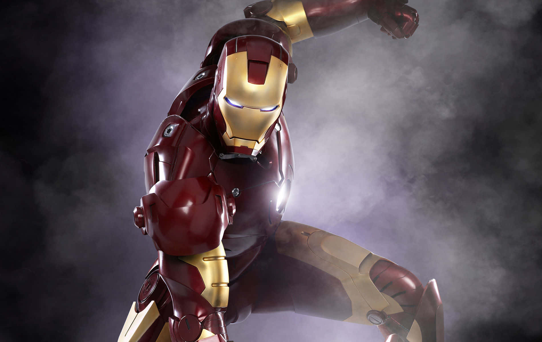 Superhero Movies 桌布 壁紙 — 身穿紅金裝甲的鋼鐵人在煙霧瀰漫的黑暗背景下擺出動感姿勢，眼睛和胸口發出光芒。