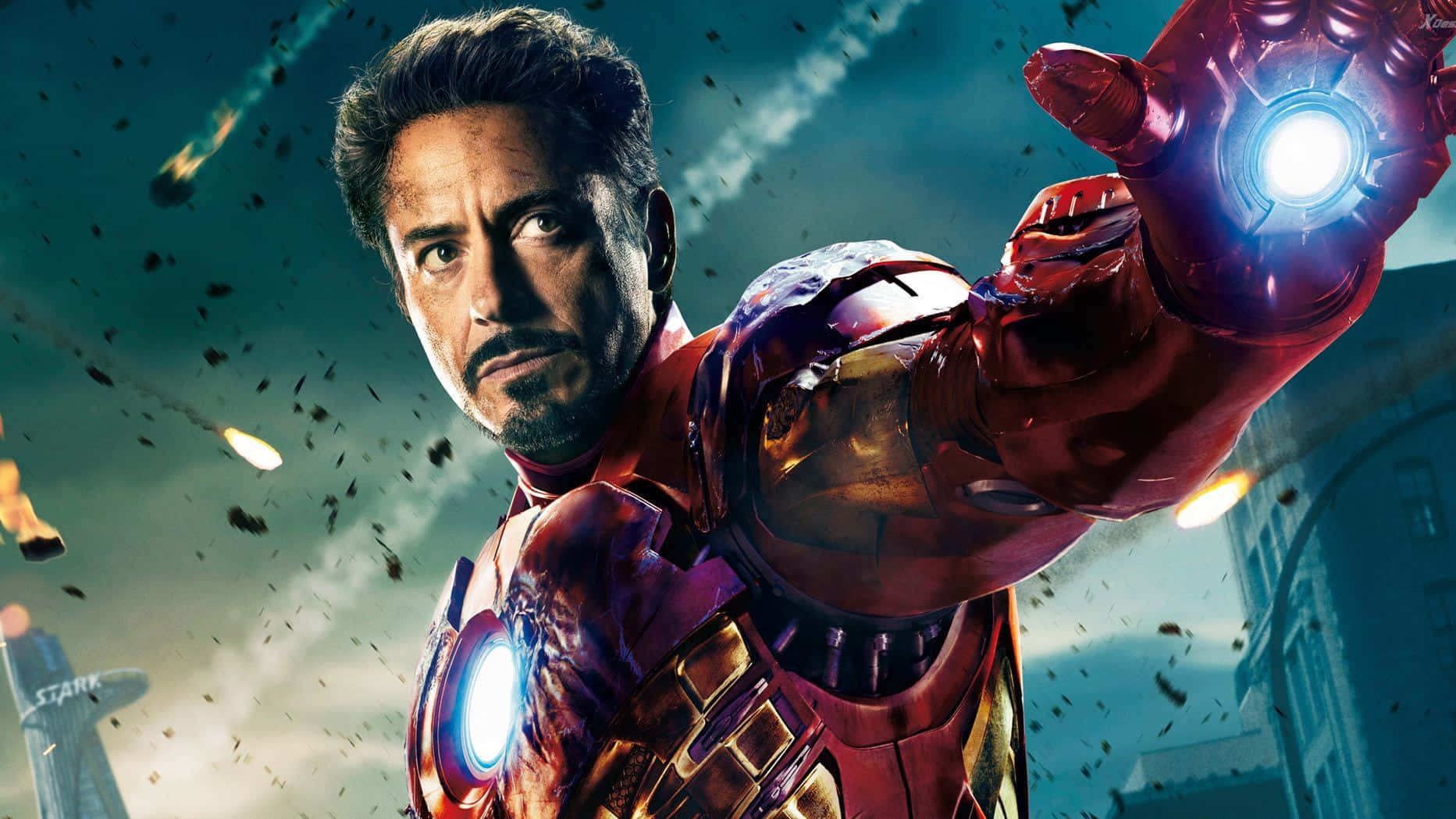 Superhero Movies 桌布 壁紙 — 身穿紅金裝甲的鋼鐵人在都市景觀中，於墜落的碎片和燃燒的彈體之間發射斥力光束。