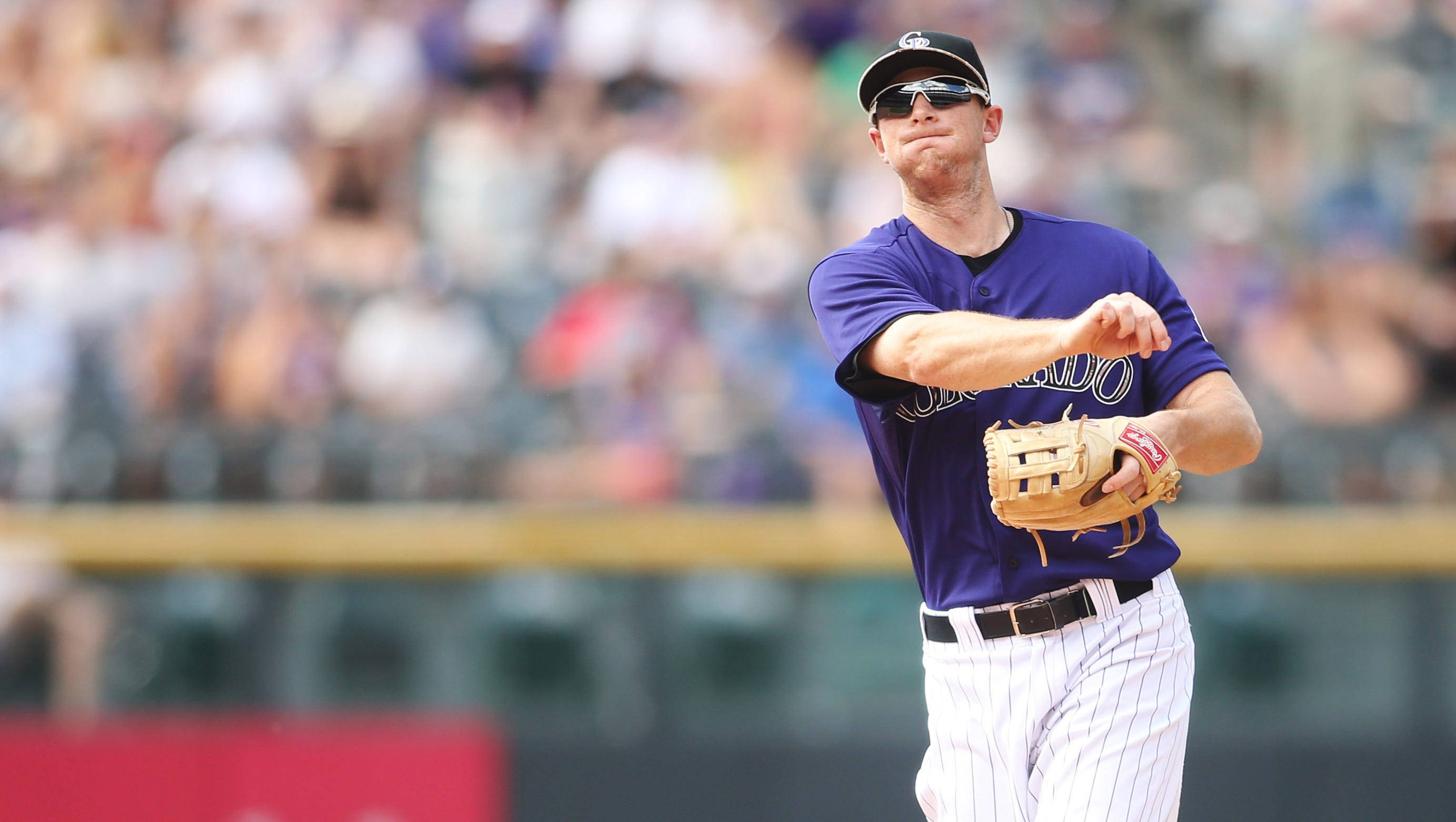Dj Lemahieu 桌布 壁紙 — 身穿紫色球衣的棒球投手在明亮的球場燈光下，背景是模糊的人群，準備投球。