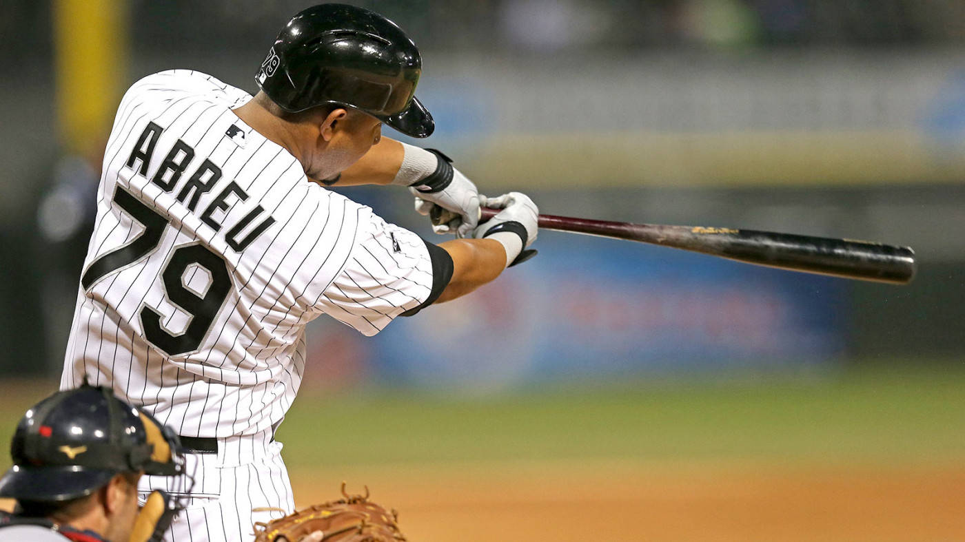 jose abreu 桌布 壁紙 — 身穿細條紋球衣的棒球選手Abreu 79號在夜間比賽中揮棒，捕手在前景。