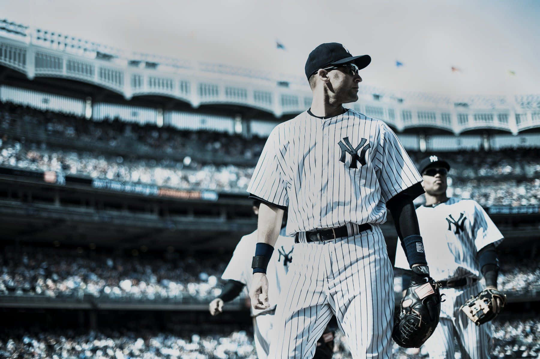 MLB Baseball League 桌布 壁紙 — 身穿細條紋球衣的棒球選手在陽光普照、坐滿觀眾的球場上走過。