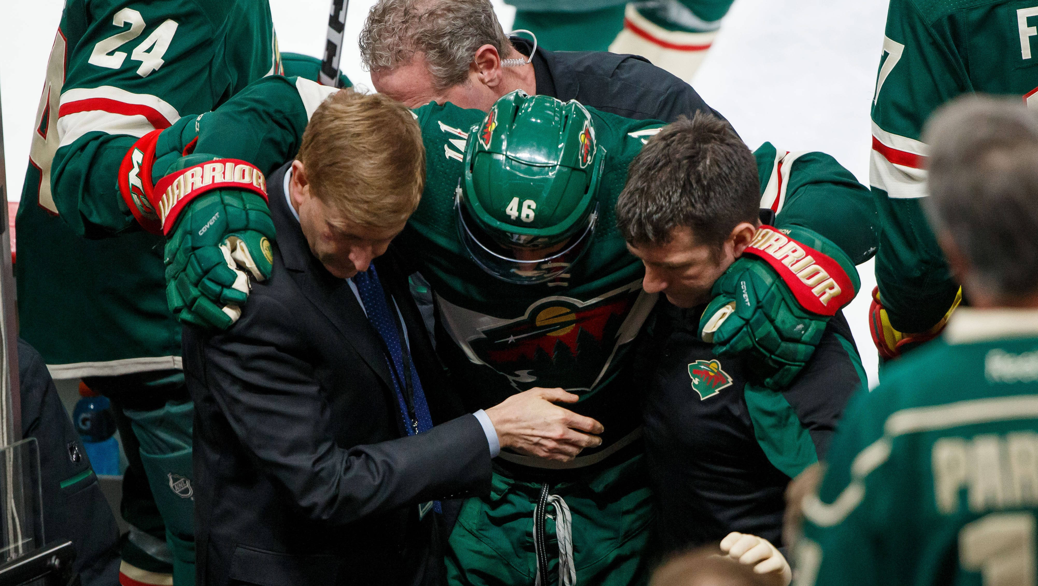 hockey 桌布 壁紙 — 身穿綠色球衣的冰球運動員圍著一位身穿西裝的教練，在冰上安慰他。