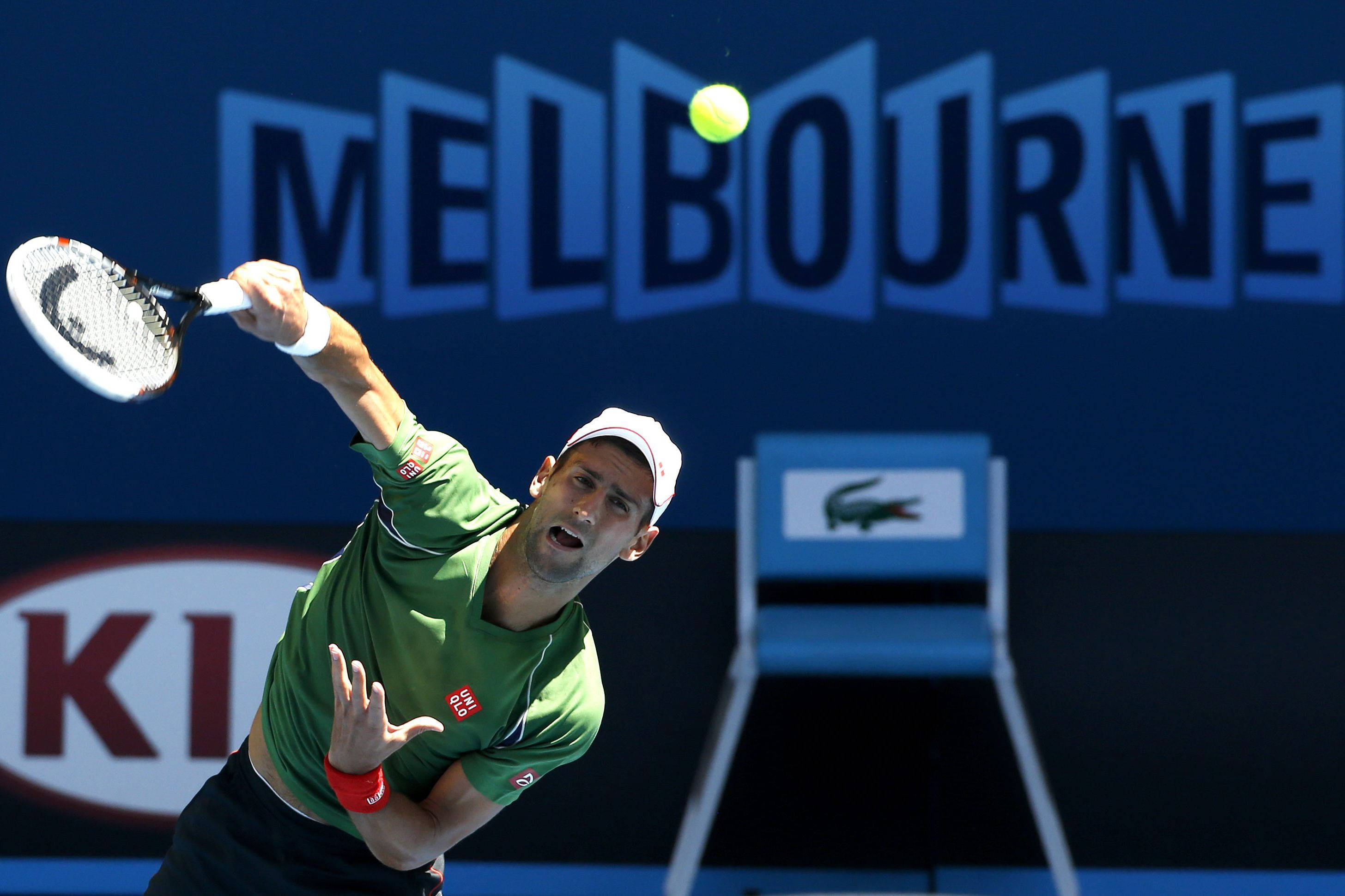 Australian Open 桌布 壁紙 — 身穿綠色球衣的網球選手用球拍擊打黃色球，背景為藍色的墨爾本。