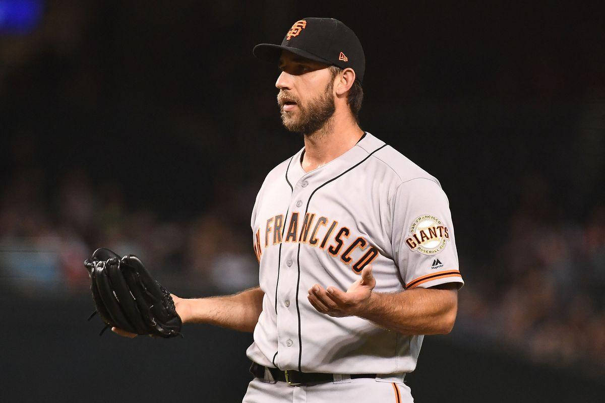 madison bumgarner 桌布 壁紙 — 身穿舊金山巨人隊球衣的棒球選手在球場燈光下，手持手套並用手勢示意。