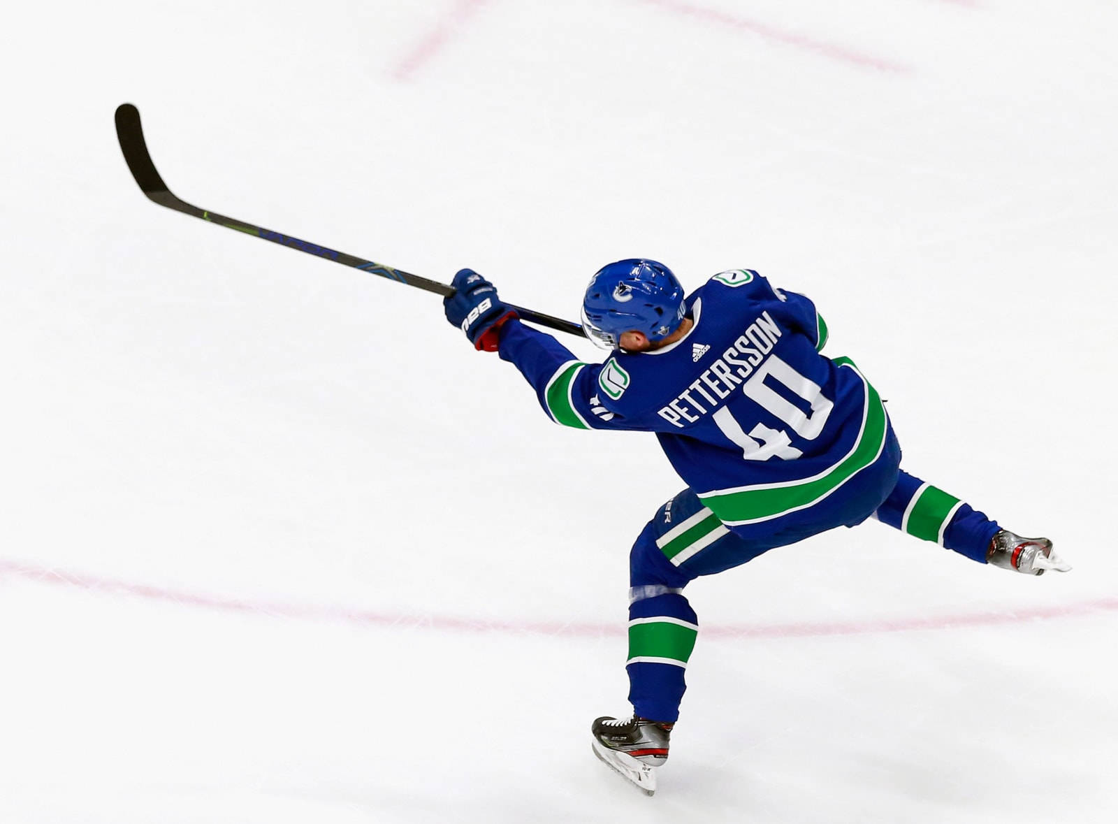 hockey 桌布 壁紙 — 身穿藍綠球衣的冰球運動員彼得森在冰上向前猛衝，球桿揮至半空。