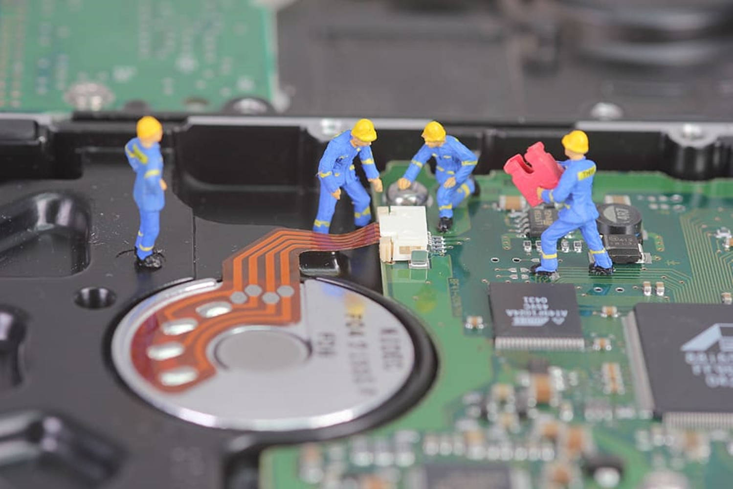 Processor 桌布 壁紙 — 身穿藍色制服和黃色頭盔的微型建築工人正在修理硬碟內的綠色電路板。