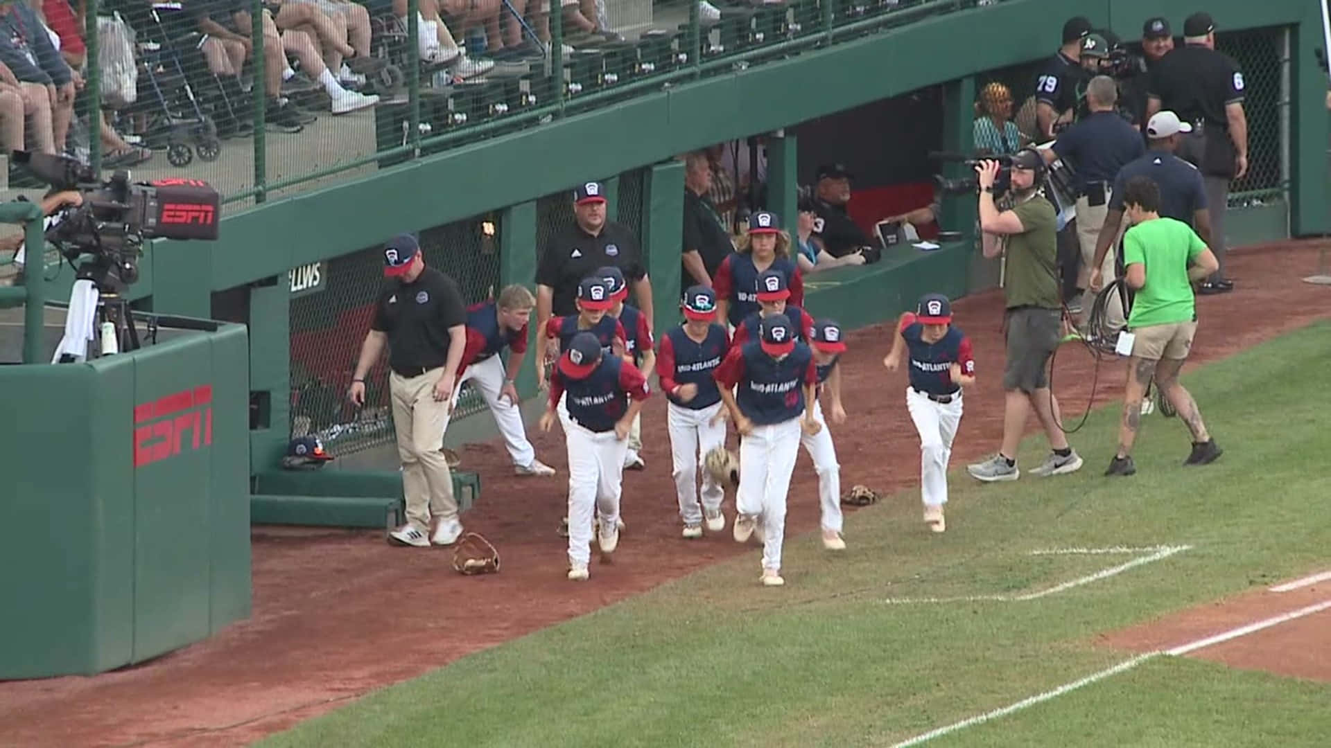 Little League Baseball 桌布 壁紙 — 身穿藍色和紅色制服的年輕棒球選手從球員休息區衝向綠色球場，相機捕捉住這個時刻。