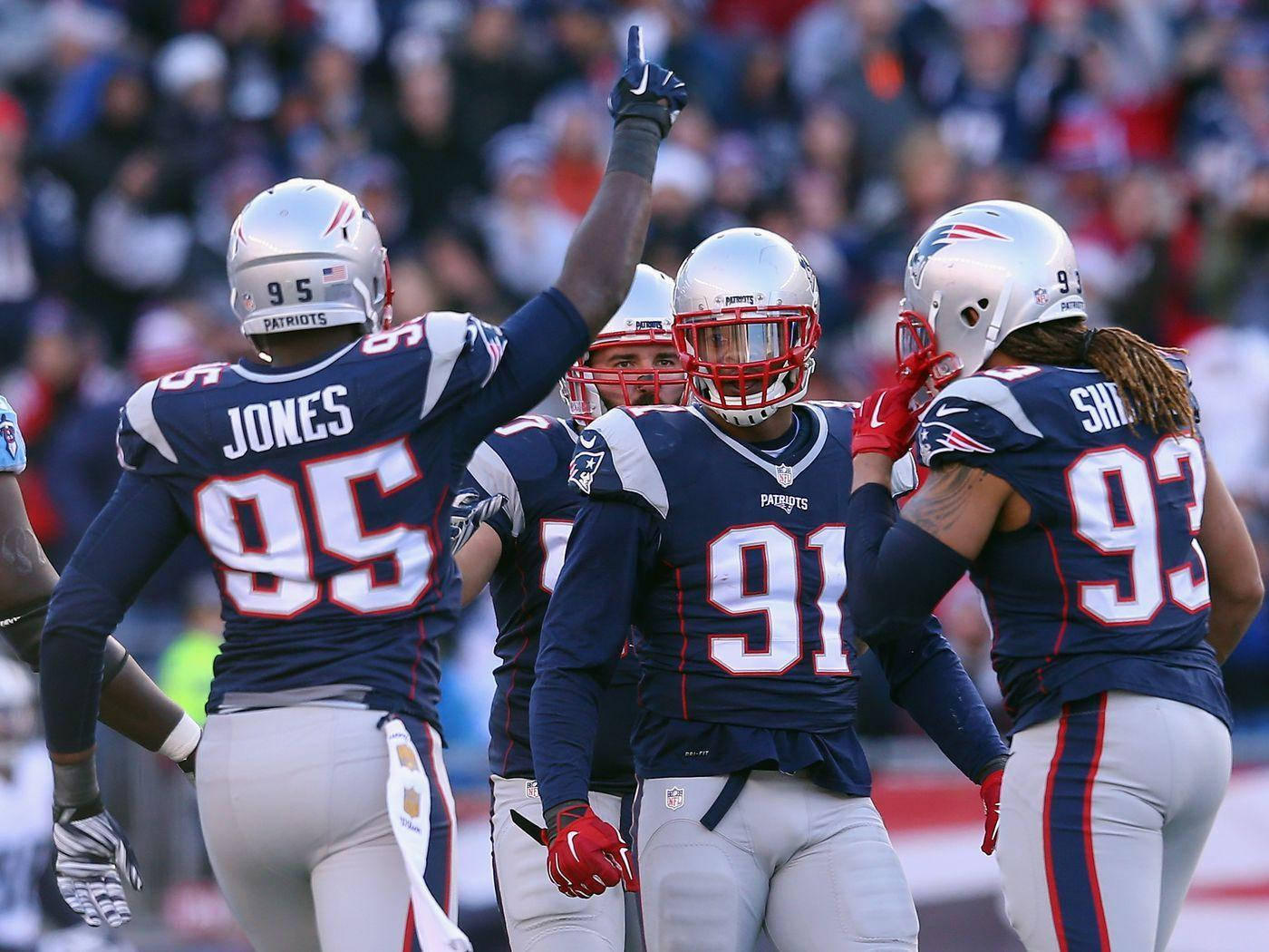 New England Patriots 桌布 壁紙 — 身穿藍色和銀色制服的新英格蘭愛國者隊美式足球員在球場上高舉手臂和頭盔慶祝比賽。
