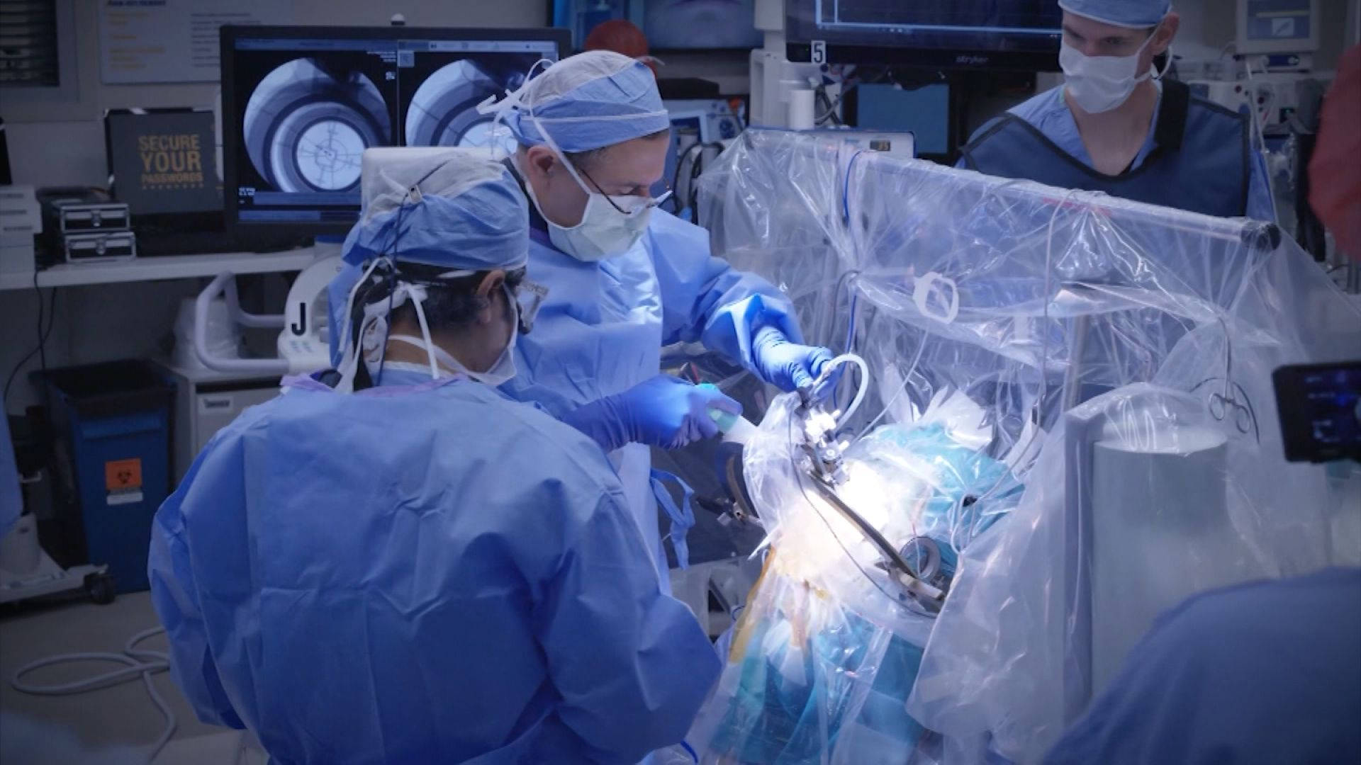 Medical 桌布 壁紙 — 身穿藍色手術衣的外科醫生在明亮燈光下的高科技手術室中進行精細手術。