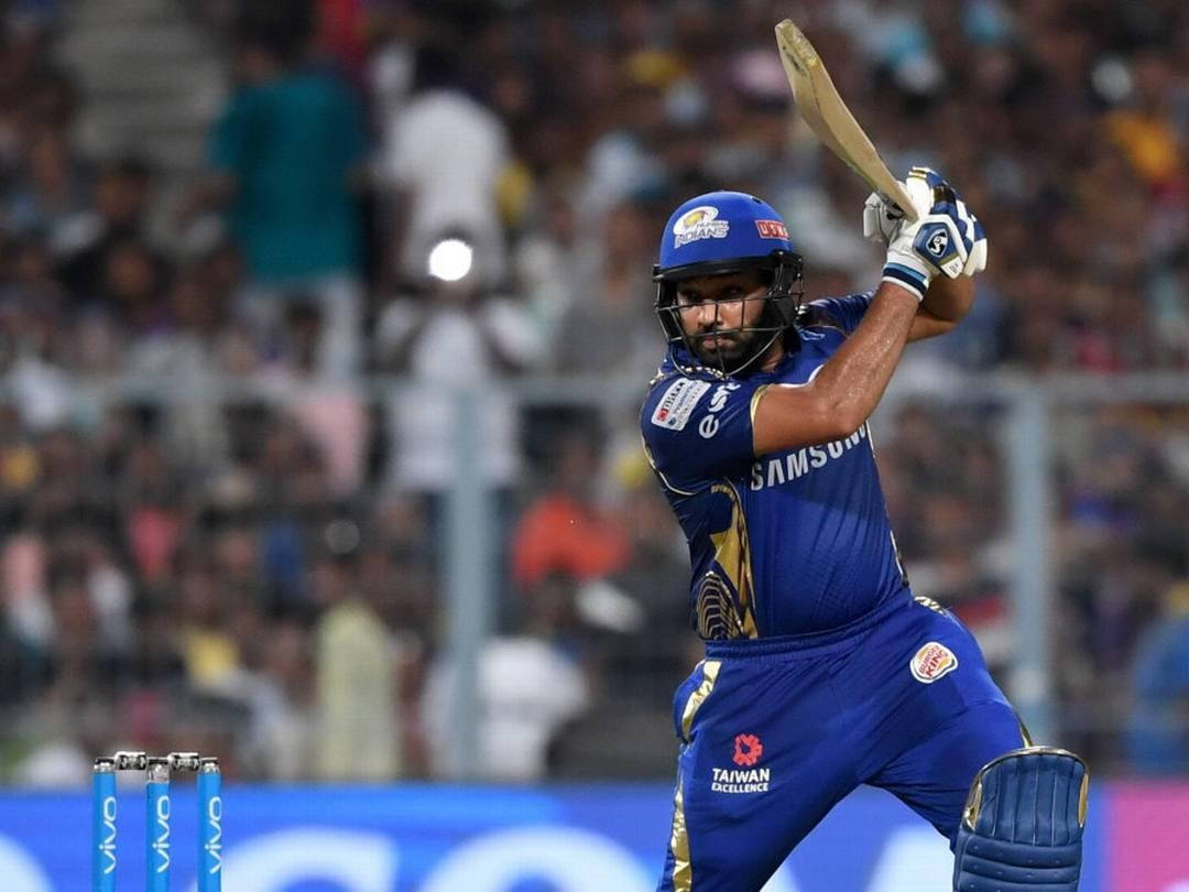 Mumbai Indians 桌布 壁紙 — 身穿藍色球衣的板球擊球手在球場燈光下揮棒中，背景是模糊的人群。