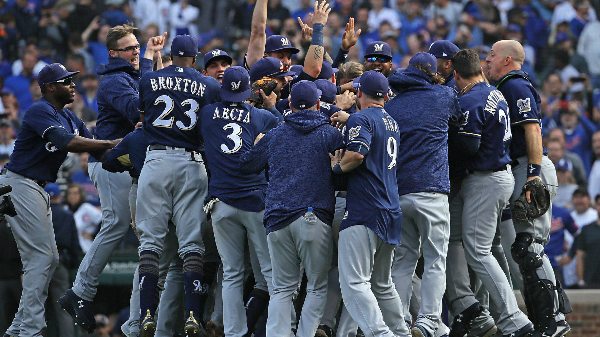 Brewers 桌布 壁紙 — 身穿藍色球衣的棒球運動員在陽光明媚的球場上緊密圍成一圈慶祝勝利，背景是歡呼的球迷。