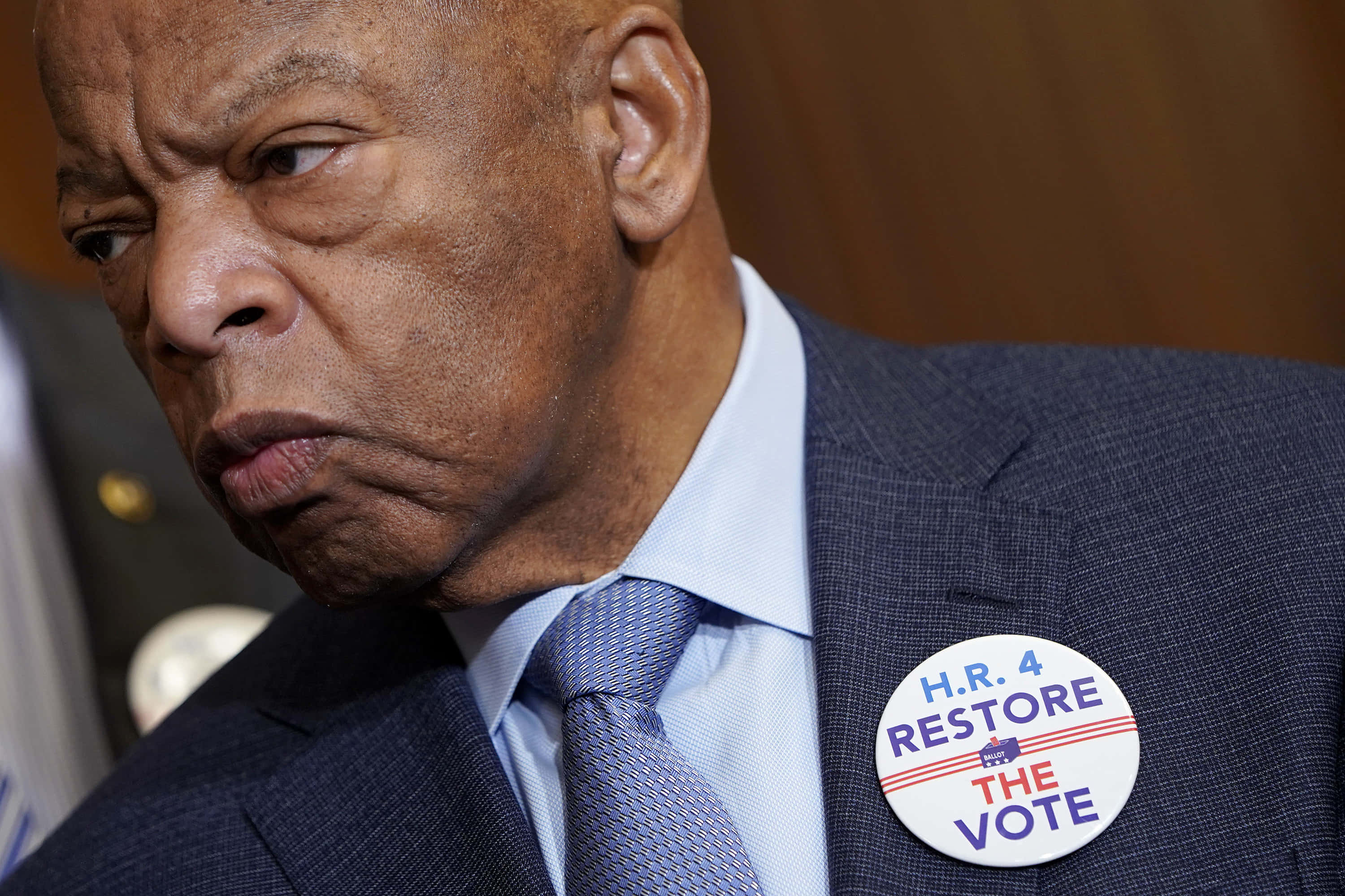 Celebrity 桌布 壁紙 — 身穿西裝、表情嚴肅的黑人男子近照，佩戴著 'H.R. 4 RESTORE THE VOTE' 徽章。