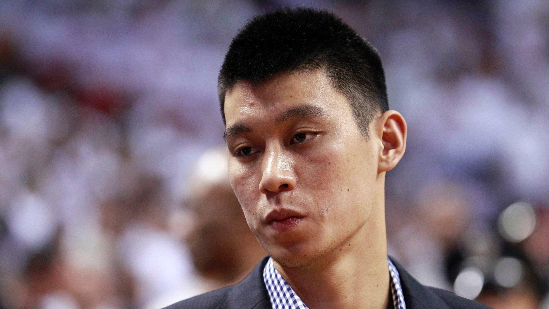Lin 桌布 壁紙 — 身穿西裝的專注籃球運動員的特寫肖像，向下看，身後是模糊的體育場人群。