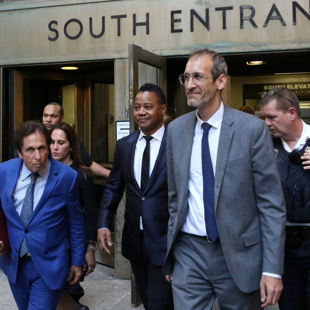 Celebrity 桌布 壁紙 — 身穿西裝的男子從法院南面出口離開，附近有警察和職員。