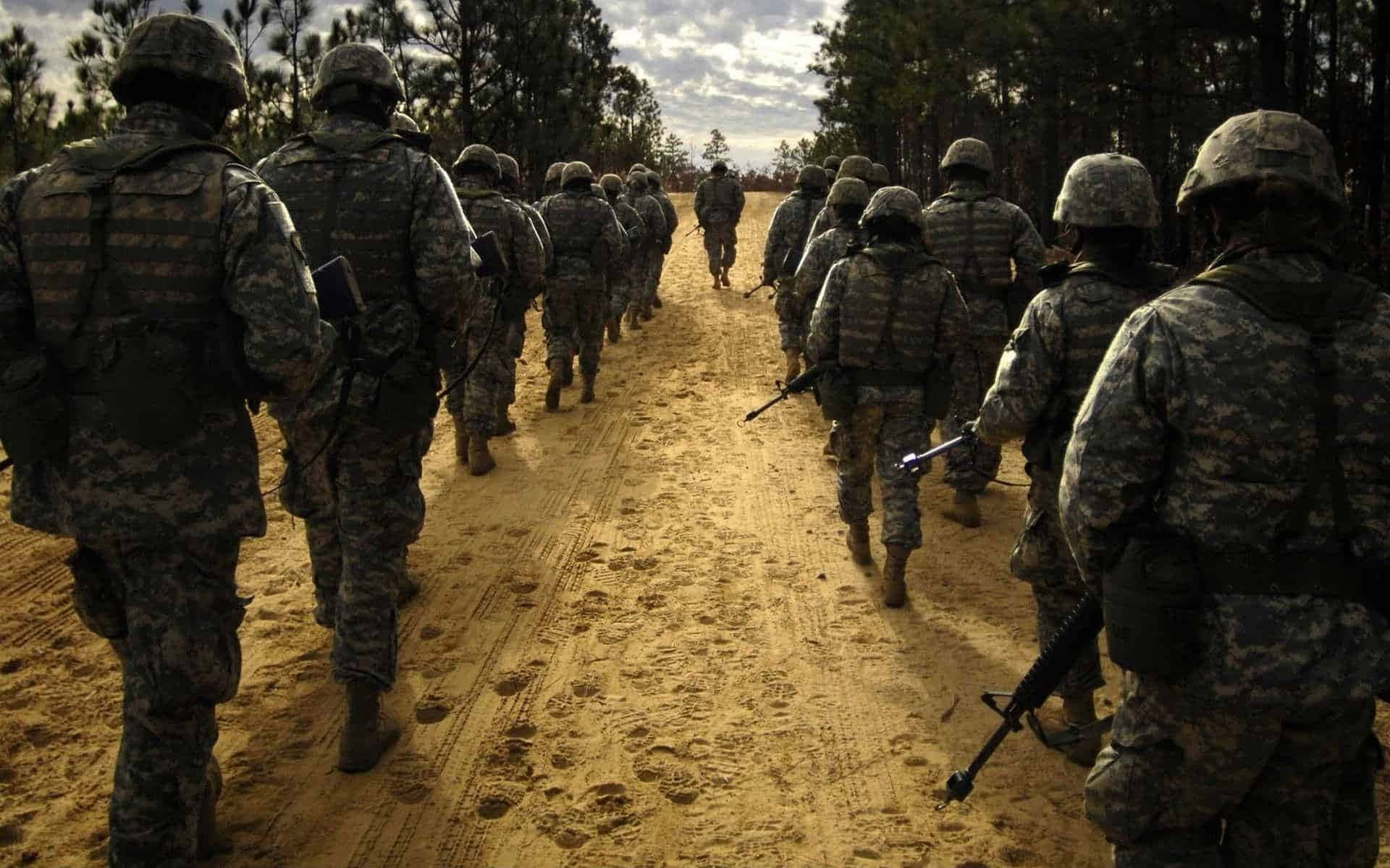 身穿迷彩服的士兵排成一列穿過森林行進。 — 軍隊 壁紙