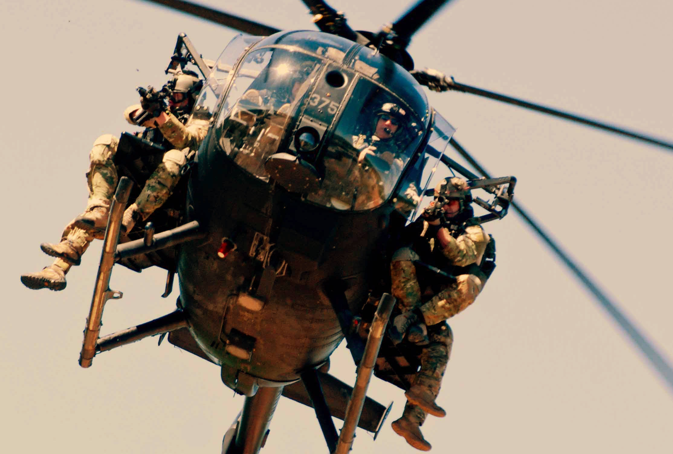 Helicopter 桌布 壁紙 — 身穿迷彩裝備的士兵懸掛在一架黑色軍用直升機上，背景是朦朧的天空。