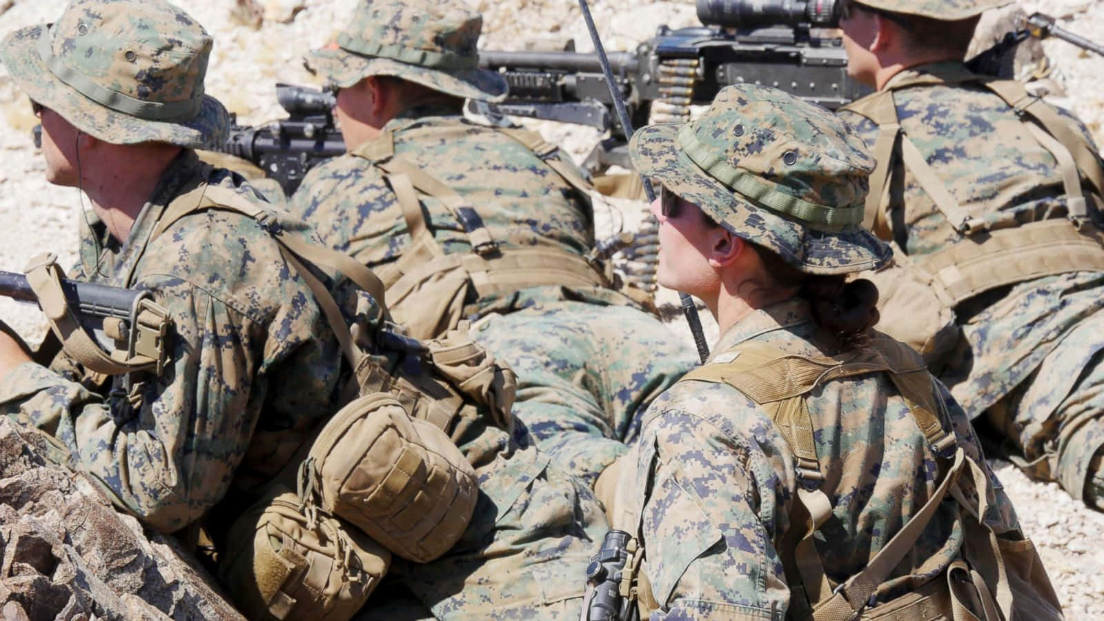 Marines 桌布 壁紙 — 身穿迷彩裝備的海軍陸戰隊員在岩石沙漠地形中蹲下，手持步槍進行訓練演習。