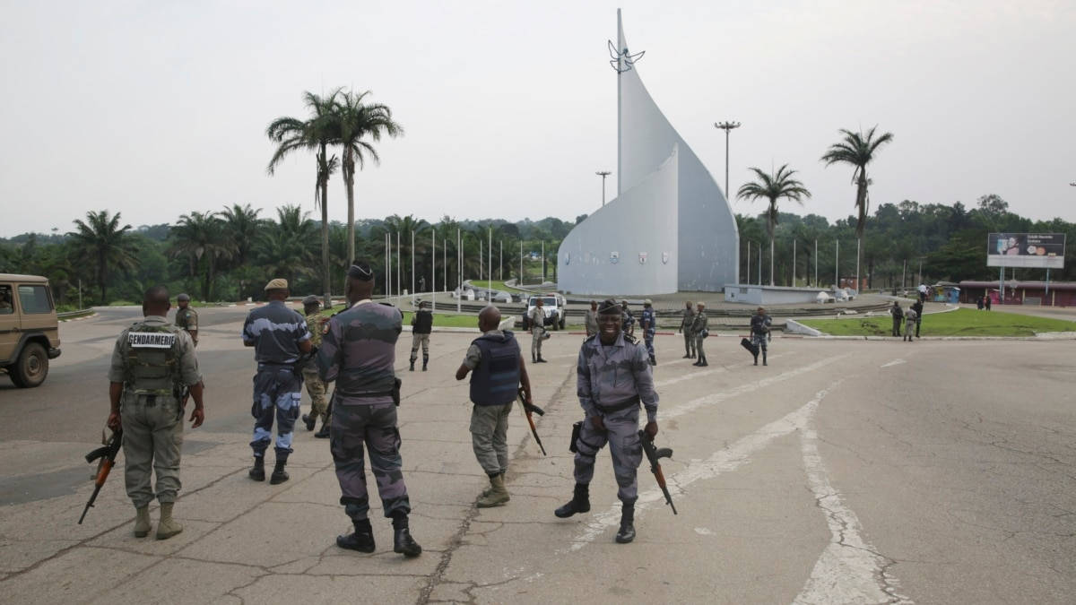 軍事動圖 桌布 壁紙 — 身穿迷彩軍服的士兵在陰天背景下，於一個大型白色紀念碑周圍站崗，背景有棕櫚樹。