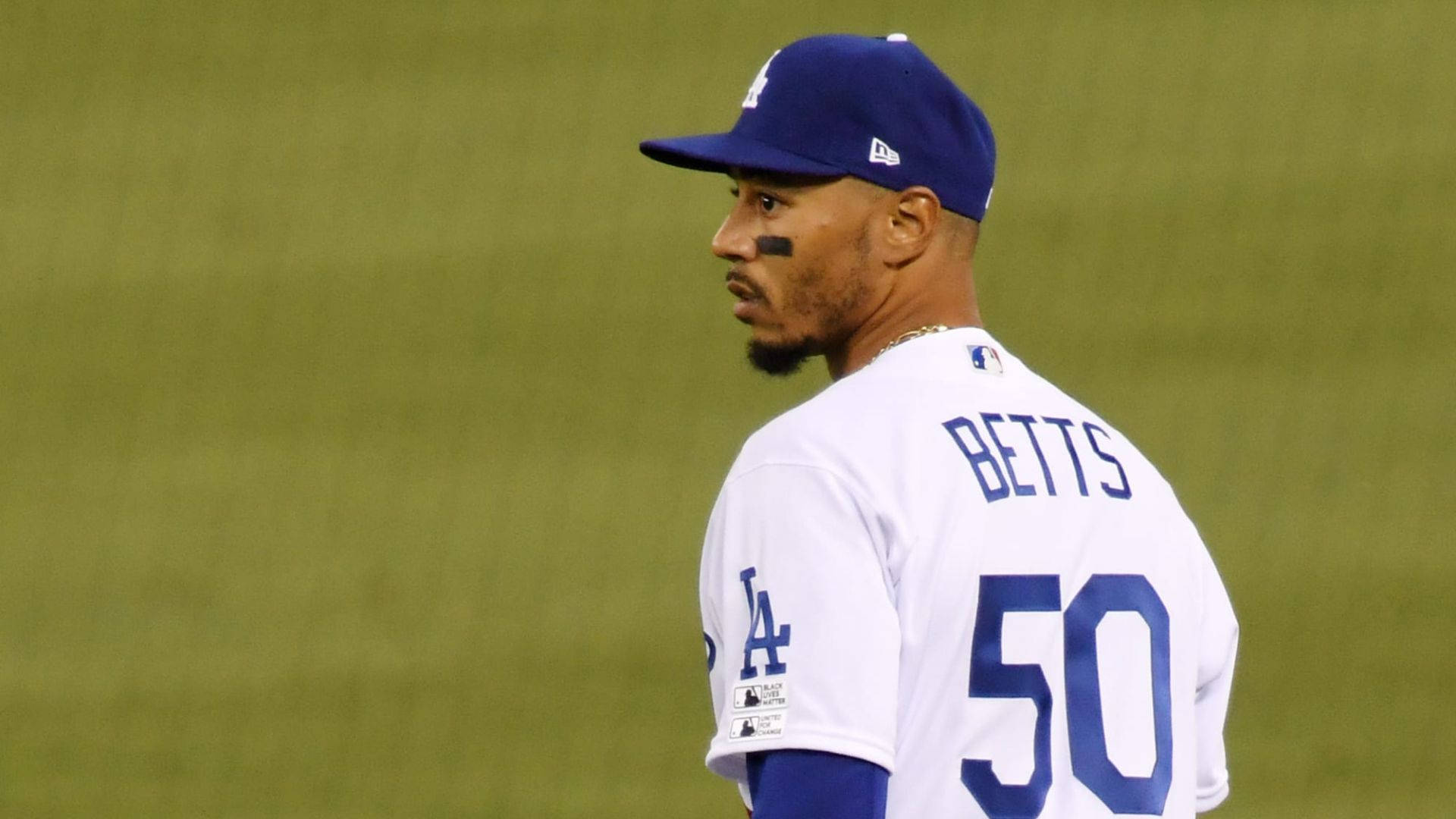 Mookie Betts 桌布 壁紙 — 身穿道奇隊球衣的棒球選手 Mookie Betts 站在球場上，專注地望向遠方。